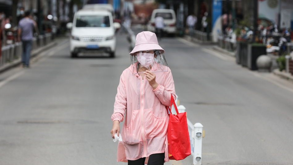 A woman wears a face mask on Monday as she walks along a street in Wuhan, in China's central Hubei province. Wuhan reported new cases of COVID-19 after going more than a month without new infections. (Stringer/AFP via Getty Images)