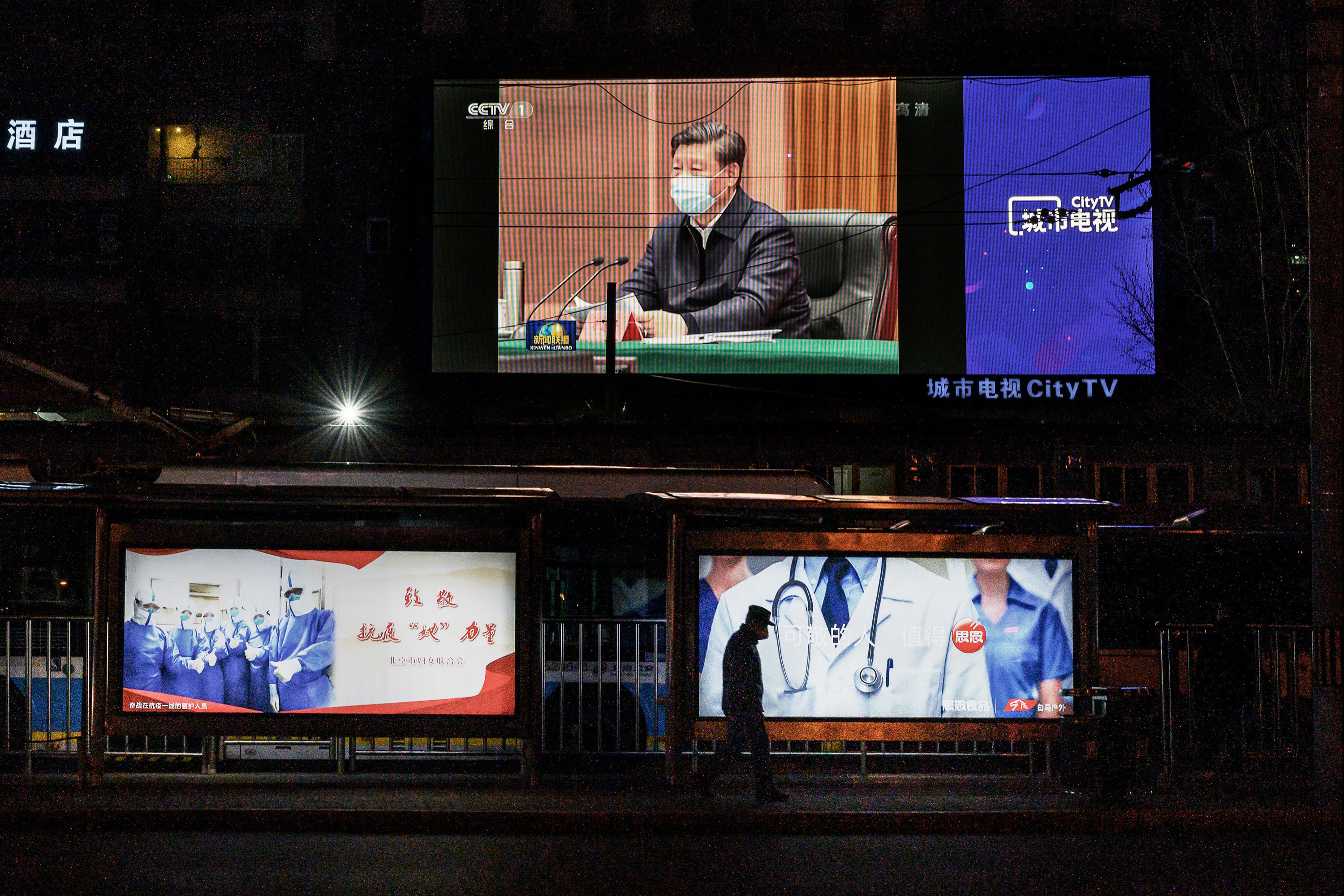 A large screen broadcasting an evening newscast along a Beijing street in March shows Chinese President Xi Jinping wearing a protective mask during his visit to Wuhan earlier in the day. (Getty Images)