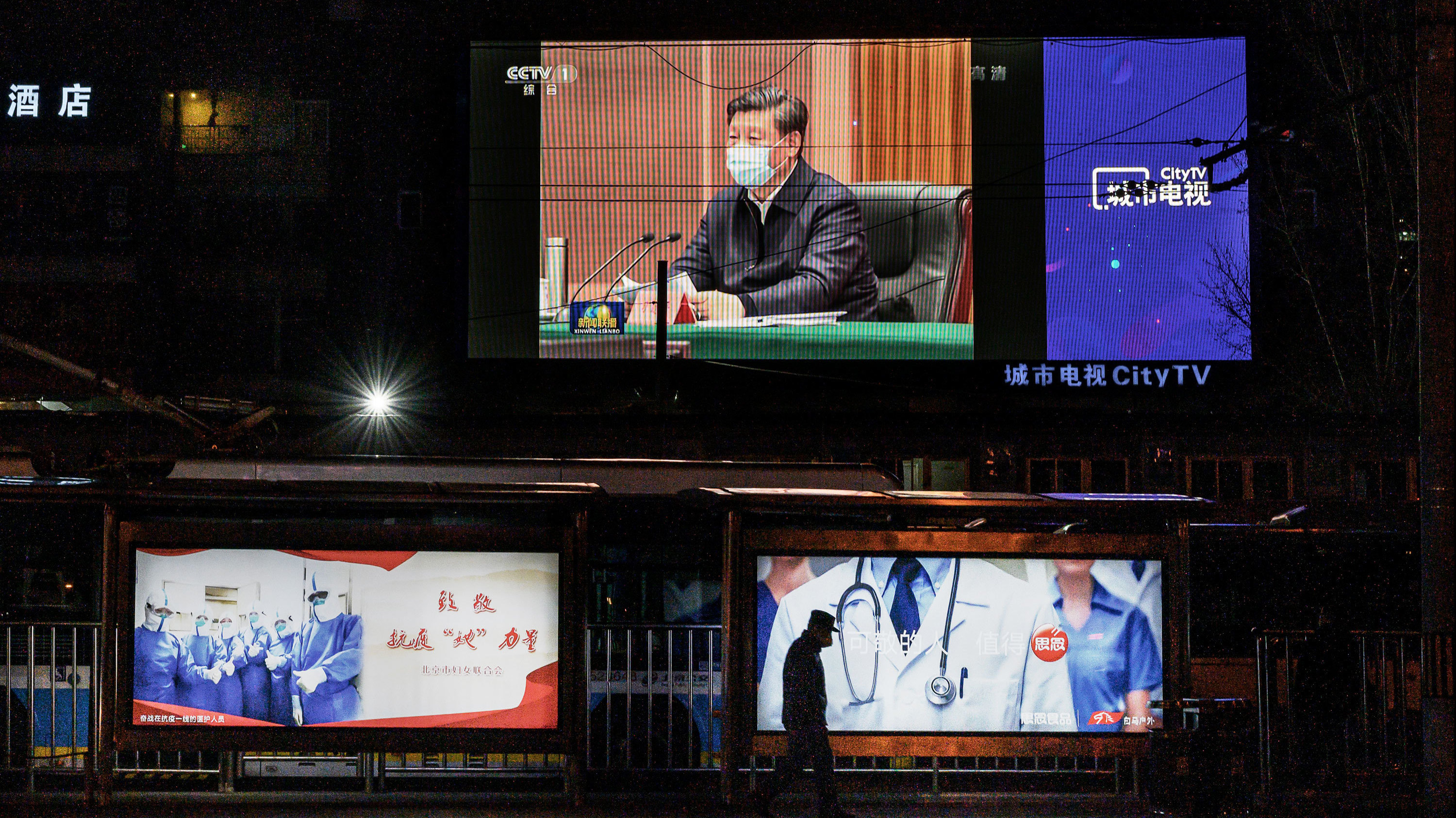 A large screen in the street shows Chinese leader Xi Jinping wearing a protective mask during his visit to Wuhan, China, earlier in the day, on CCTV