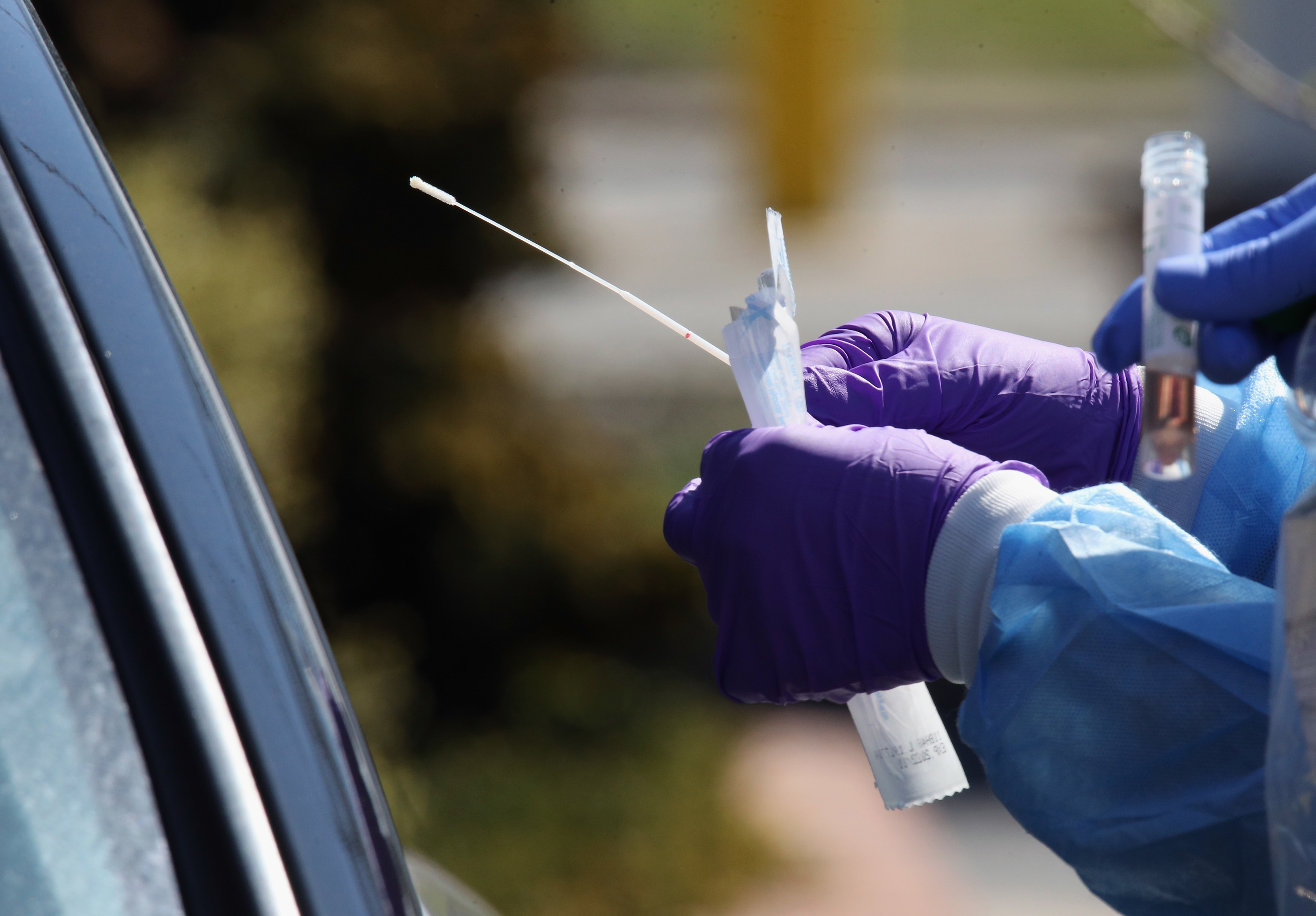Medical workers prepare to use a swab to administer a coronavirus test at a drive-through center on March 21 in Jericho, N.Y. (Getty Images)