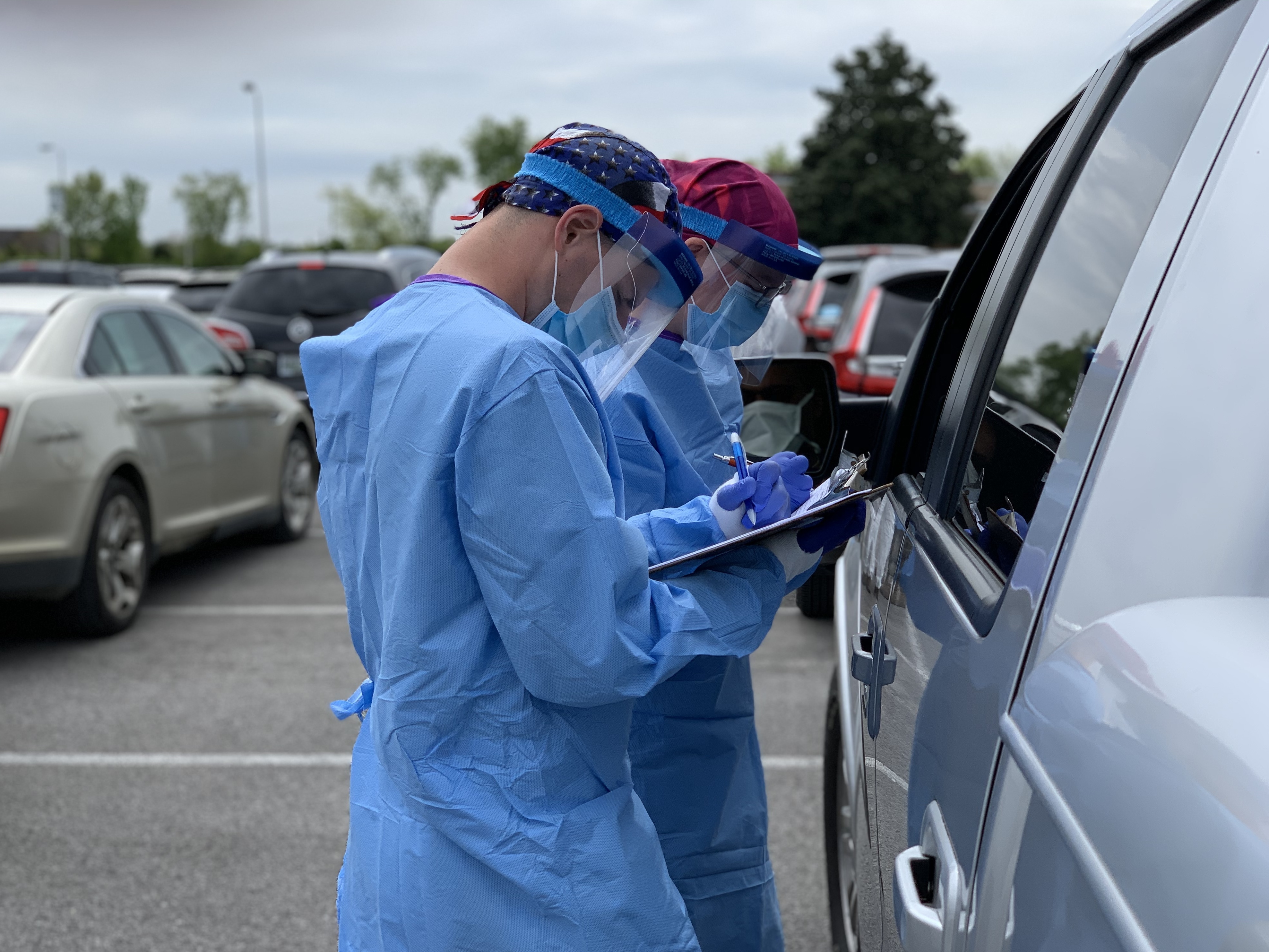 A nurse and National Guard medic interview a patient before taking a swab for a coronavirus test last month at Gallatin High School in Gallatin, Tenn. The state of Tennessee started picking up the tab for testing in April. (Blake Farmer/WPLN)
