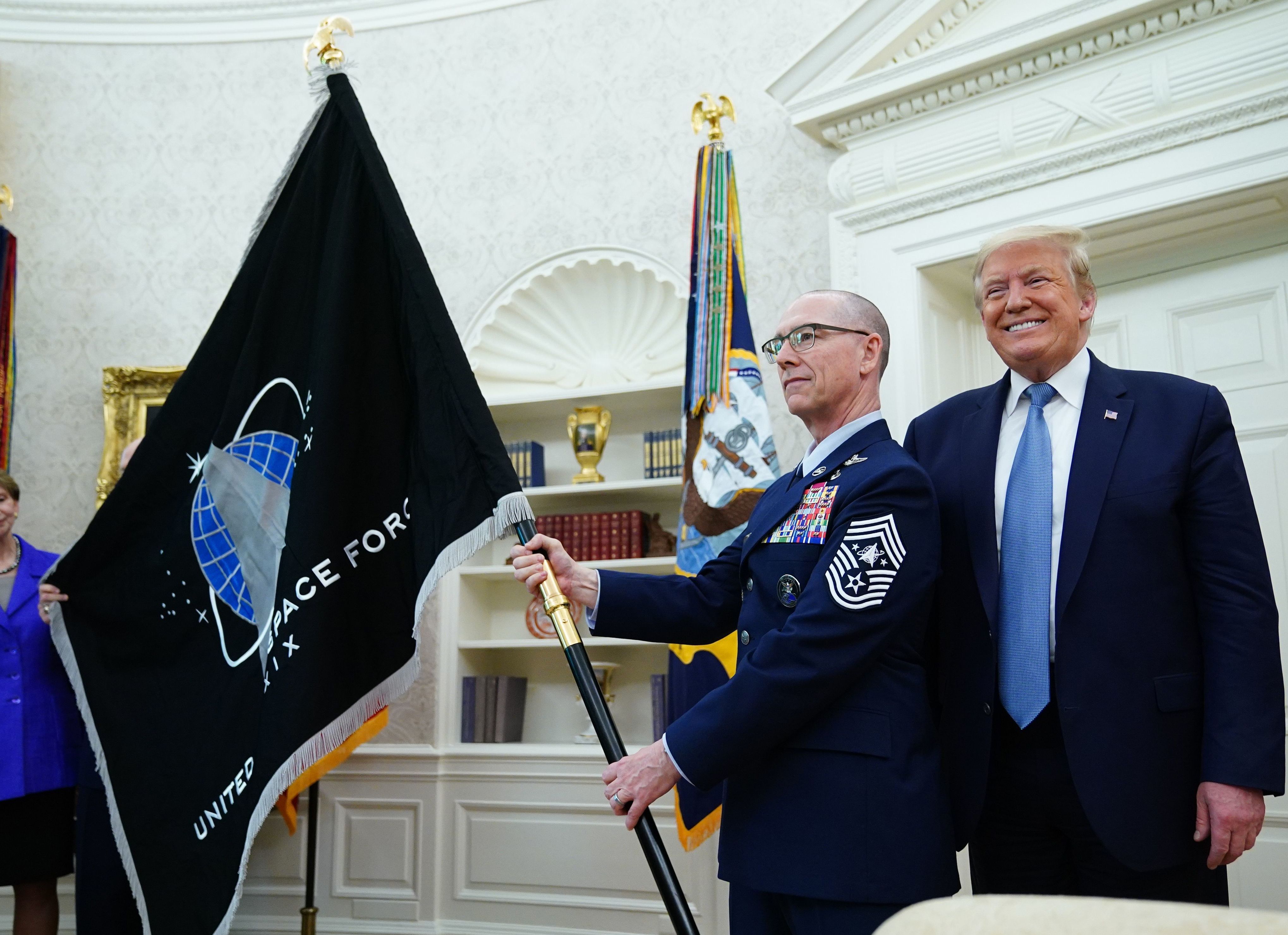 U.S. Space Force senior enlisted adviser Chief Master Sgt. Roger Towberman presents the Space Force Flag to President Trump on Friday in the Oval Office. (AFP via Getty Images)