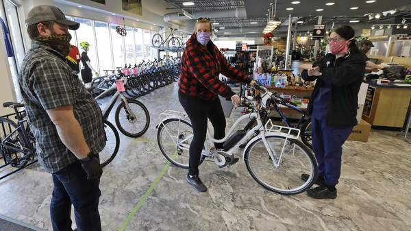 Store manager Josh Hayden, left to right, talks with Kay Amey and Jackie Gee about a new bicycle at Eddy's Bike Shop on Tuesday in Willoughby Hills, Ohio. Bike shops in most states were exempt from shutdown orders and sales have been up.