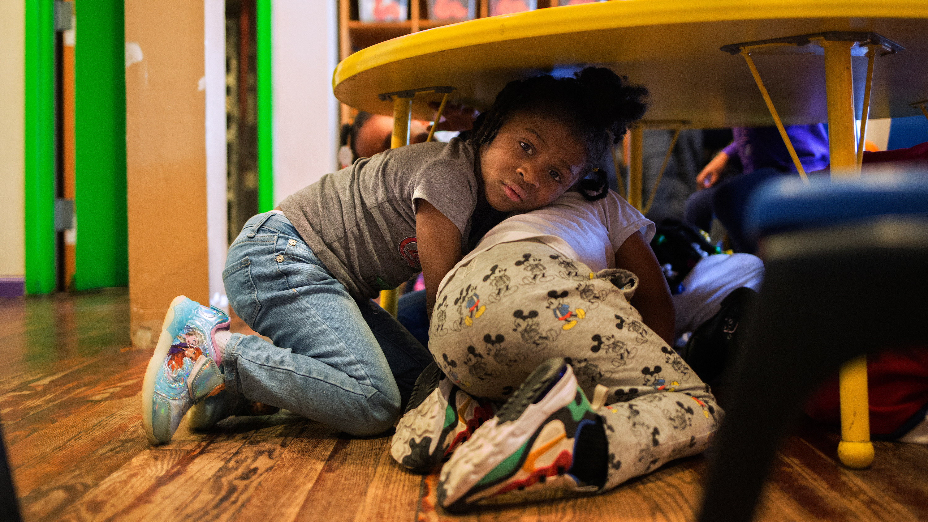 Justice Buress, 4, hides under a table while demonstrating a drill at Little Explorers Learning Center in St. Louis. Tess Trice, head of the day care program, carries out monthly drills to train the children to get on the floor when they hear gunfire. (Carolina Hidalgo/St. Louis Public Radio)