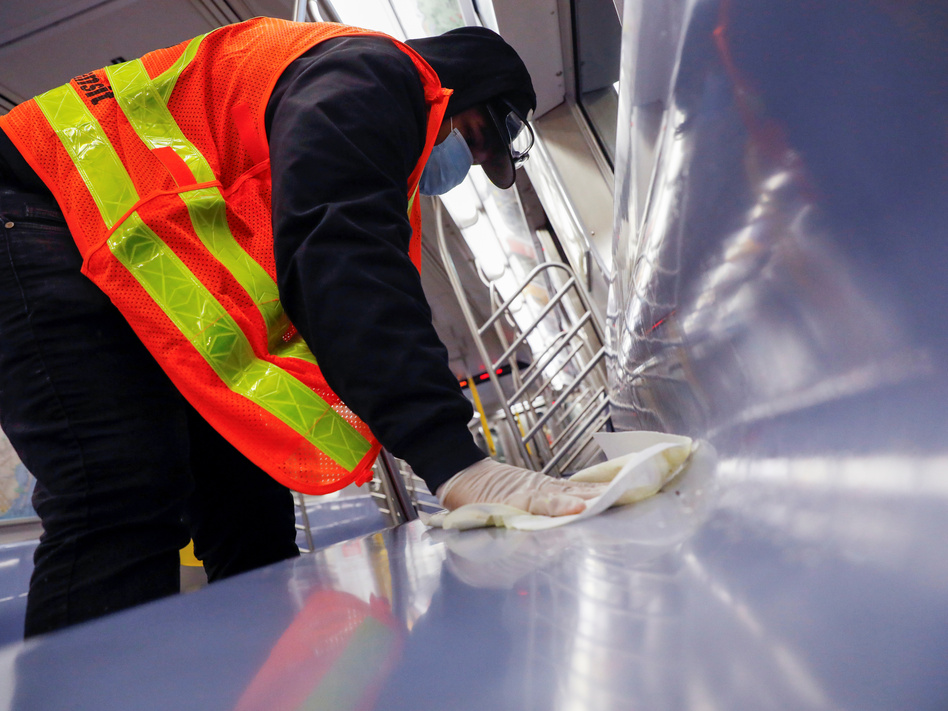 A worker wipes down surfaces on a New York City subway car to disinfect seats during the coronavirus outbreak. The CDC is clarifying its guidance on touching surfaces after a change to its website triggered news reports. (Andrew Kelly/Reuters)