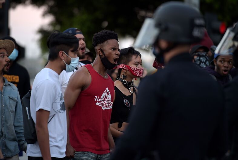 Protesters react in front of police as they gather in downtown Los Angeles on Wednesday to demonstrate George Floyd's death. (Agustin Paullier/AFP via Getty Images)