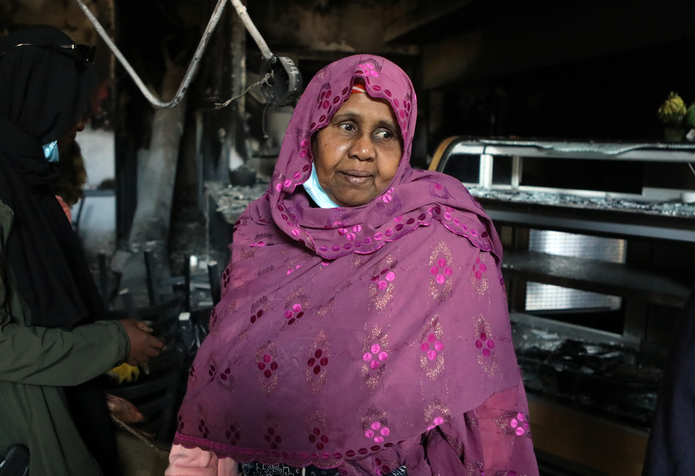 Safia Munye looks over the remains of her restaurant, Mama Safia's Kitchen, on Saturday. It was destroyed last week during protests in Minneapolis. (Jim Urquhart for NPR)