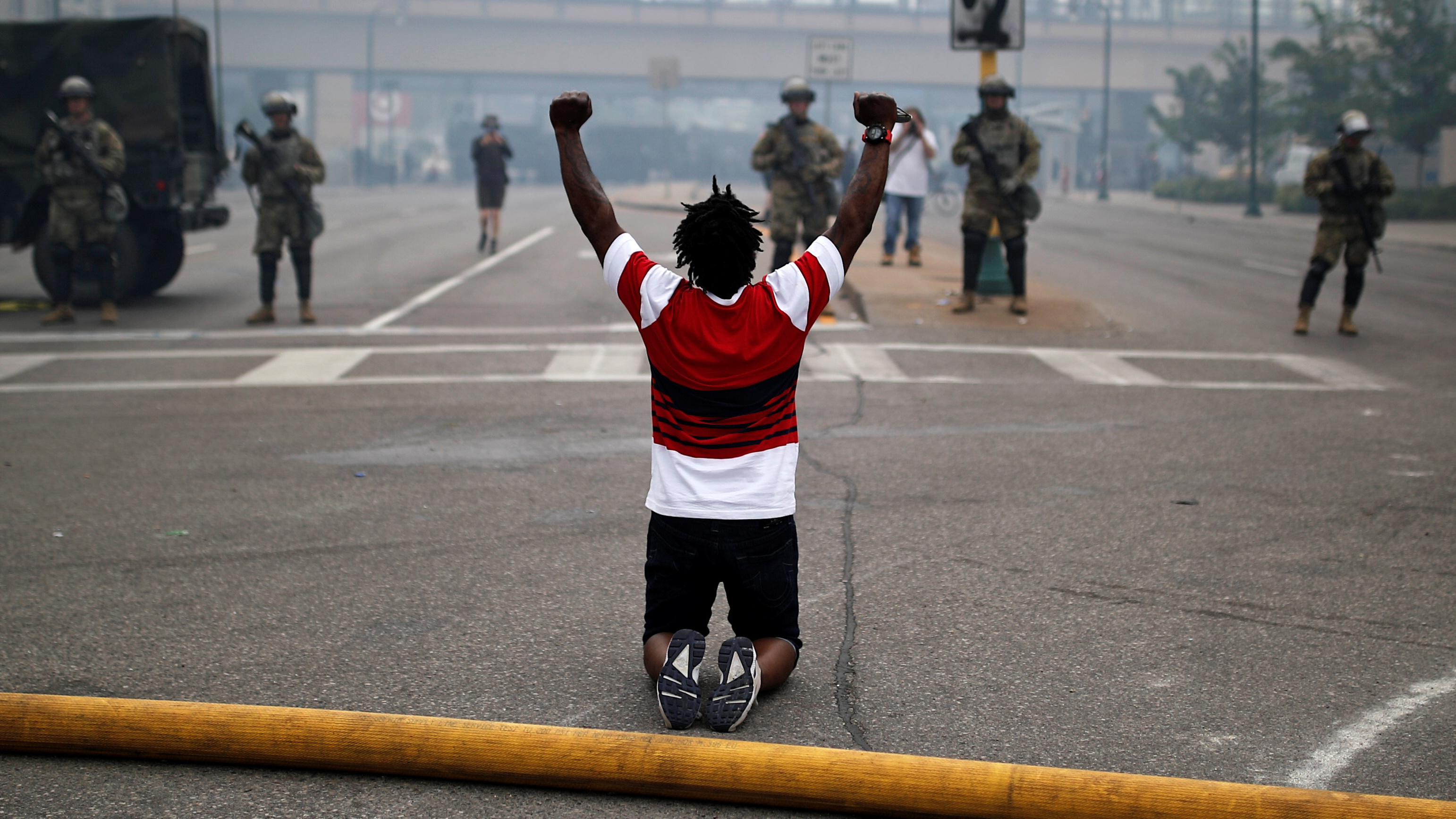 A man kneels as he confronts National Guard members guarding the area in the aftermath of a protest in Minneapolis. (Reuters)