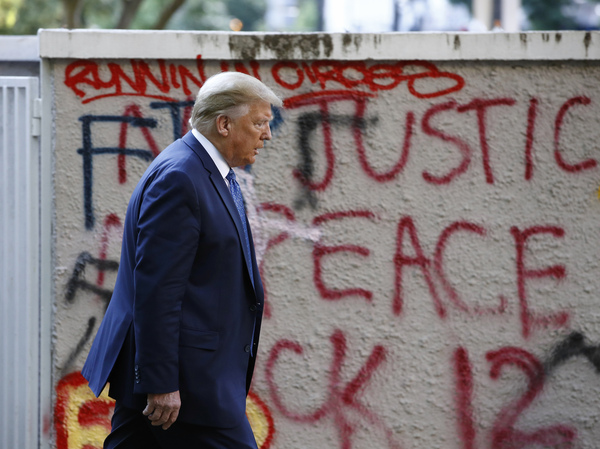 President Trump walks past protest graffiti in Lafayette Park, near the White House, on his way to visit St. John's Church on Monday.