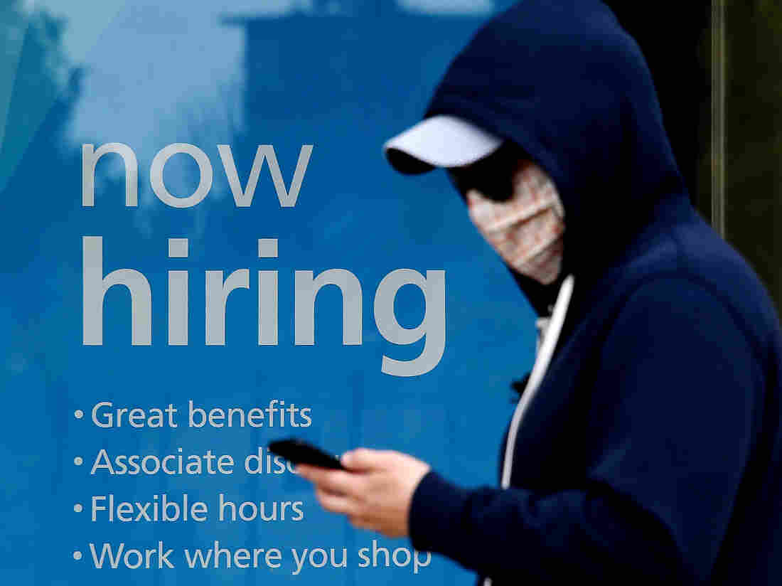 A man wearing a face mask walks past a sign "Now Hiring" in front of a store amid the coronavirus pandemic on May 14, 2020 in Arlington, Virginia. - Another 3 million people filed initial unemployment claims last week on a seasonally adjusted basis, according to the Department of Labor. (Photo by Olivier DOULIERY / AFP) (Photo by OLIVIER DOULIERY/AFP via Getty Images)