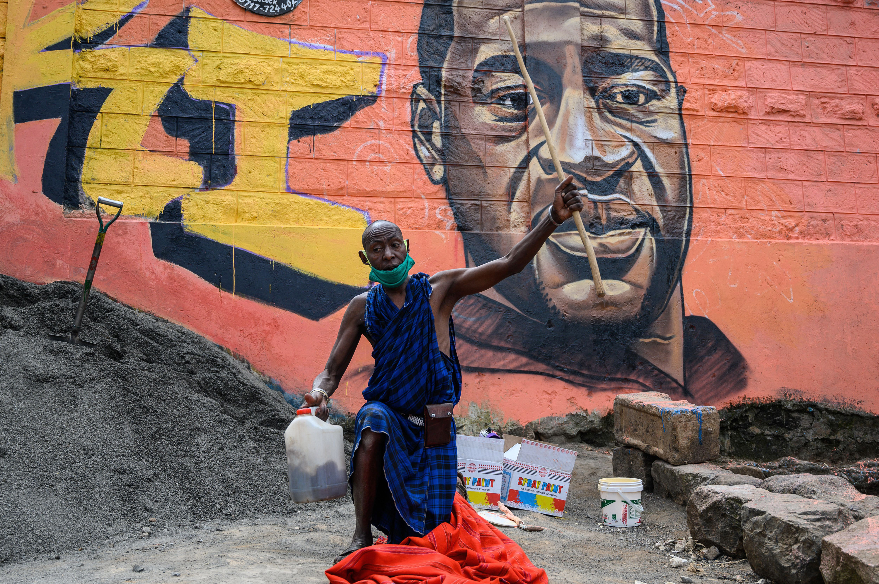 A Maasai man in the Kibera slum of Nairobi, Kenya, prays next to a mural of George Floyd, painted by the artist Allan Mwangi on June 3. (AFP via Getty Images)