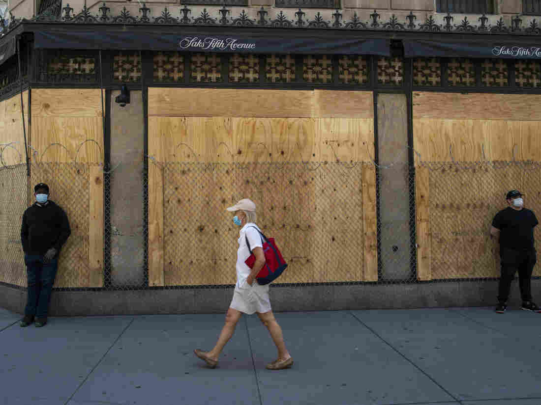 NEW YORK, NEW YORK - JUNE 08: A woman walks by a boarded up Saks store in New York City. The city began the first phase of reopening after nearly three months of being shutdown due to the coronavirus pandemic. (Photo by Kena Betancur/VIEWpress via Getty Images)