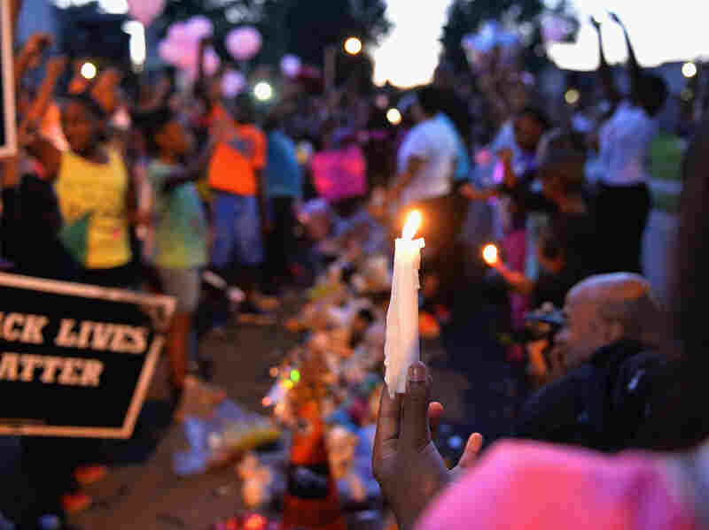 A girl holds a candle as children gather at the Michael Brown Jr. memorial on Canfield Drive during a candlelight vigil.