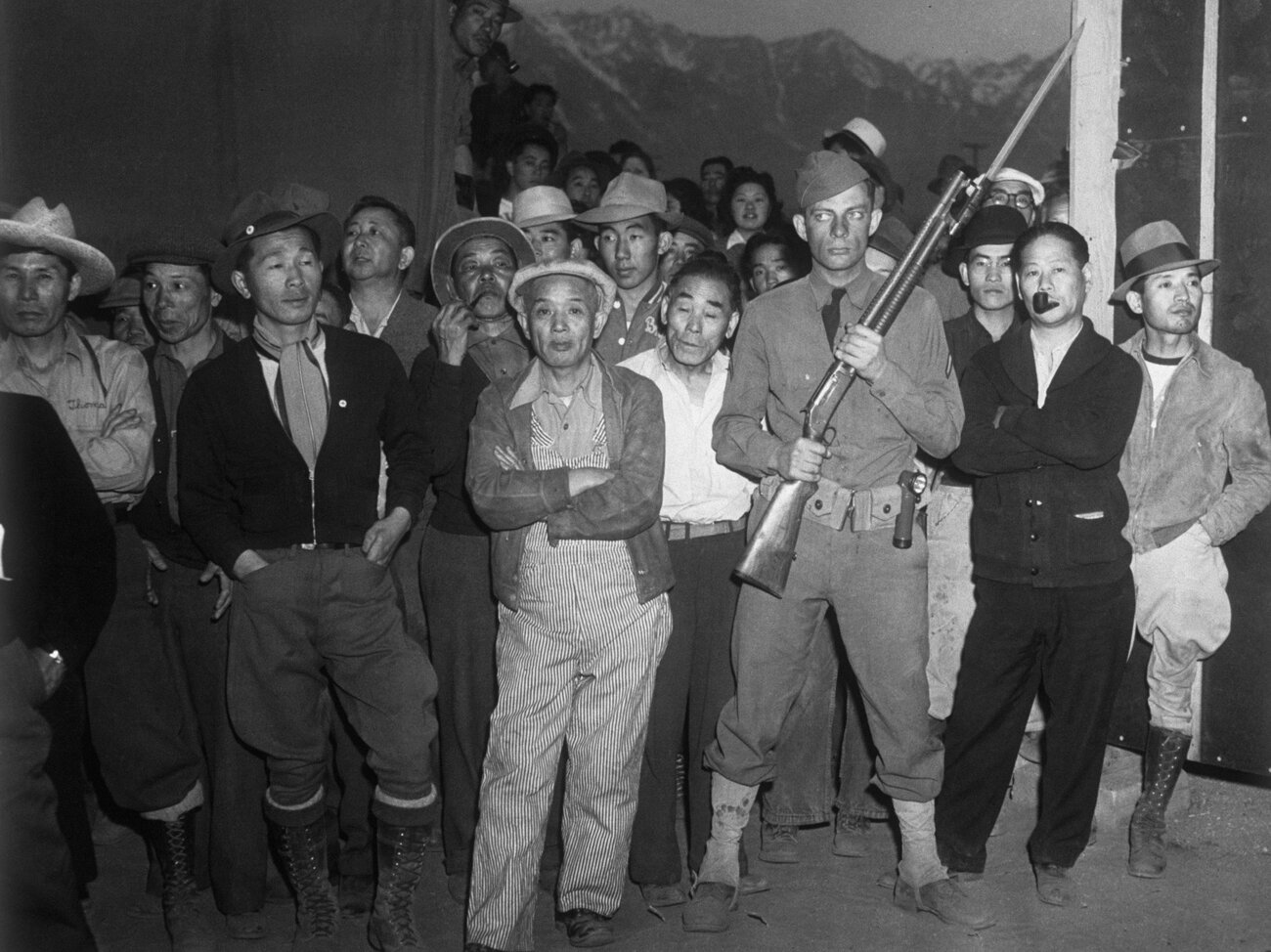 An American soldier guarding a crowd of Japanese American internees at an i...
