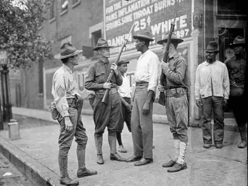 Armed National Guards and African American men standing on a sidewalk during the race riots in Chicago, Illinois, 1919.
