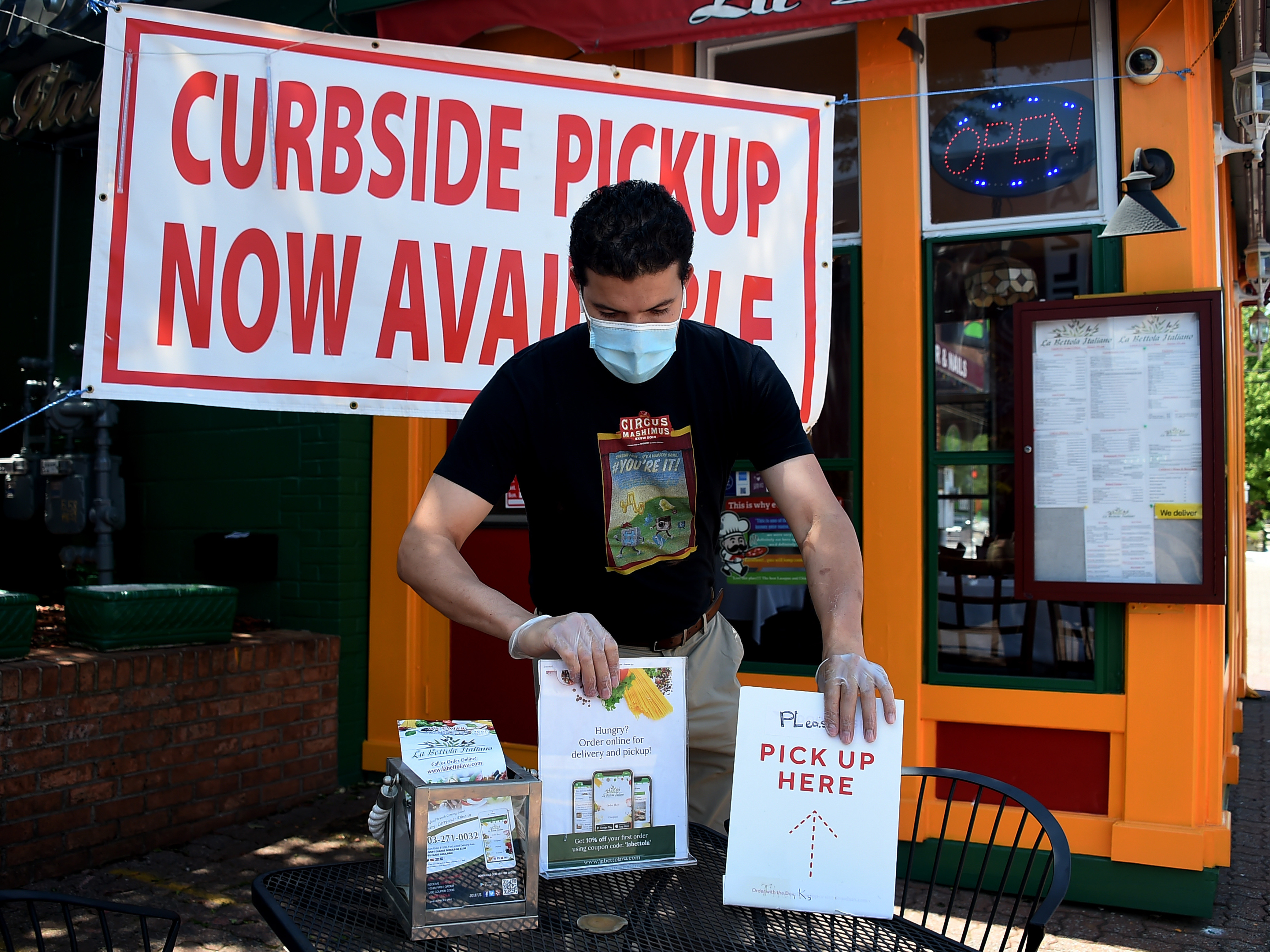 An employee sets a table for pickup orders at a restaurant in Arlington, Va. Even as states are moving to reopen their economies, tens of millions are out of work. (AFP via Getty Images)