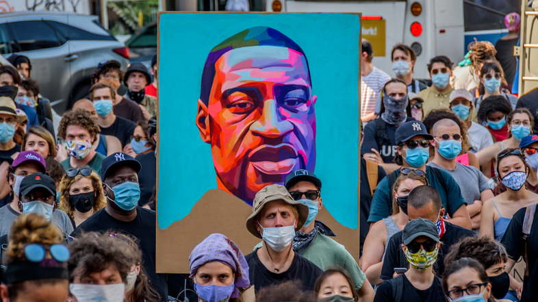 Protesters hold a portrait of George Floyd at a demonstration against police brutality in New York City. Policing "wasn't always this big. It wasn't always this bureaucratic," journalist Jamiles Lartey says. (Erik McGregor/LightRocket via Getty Images)
