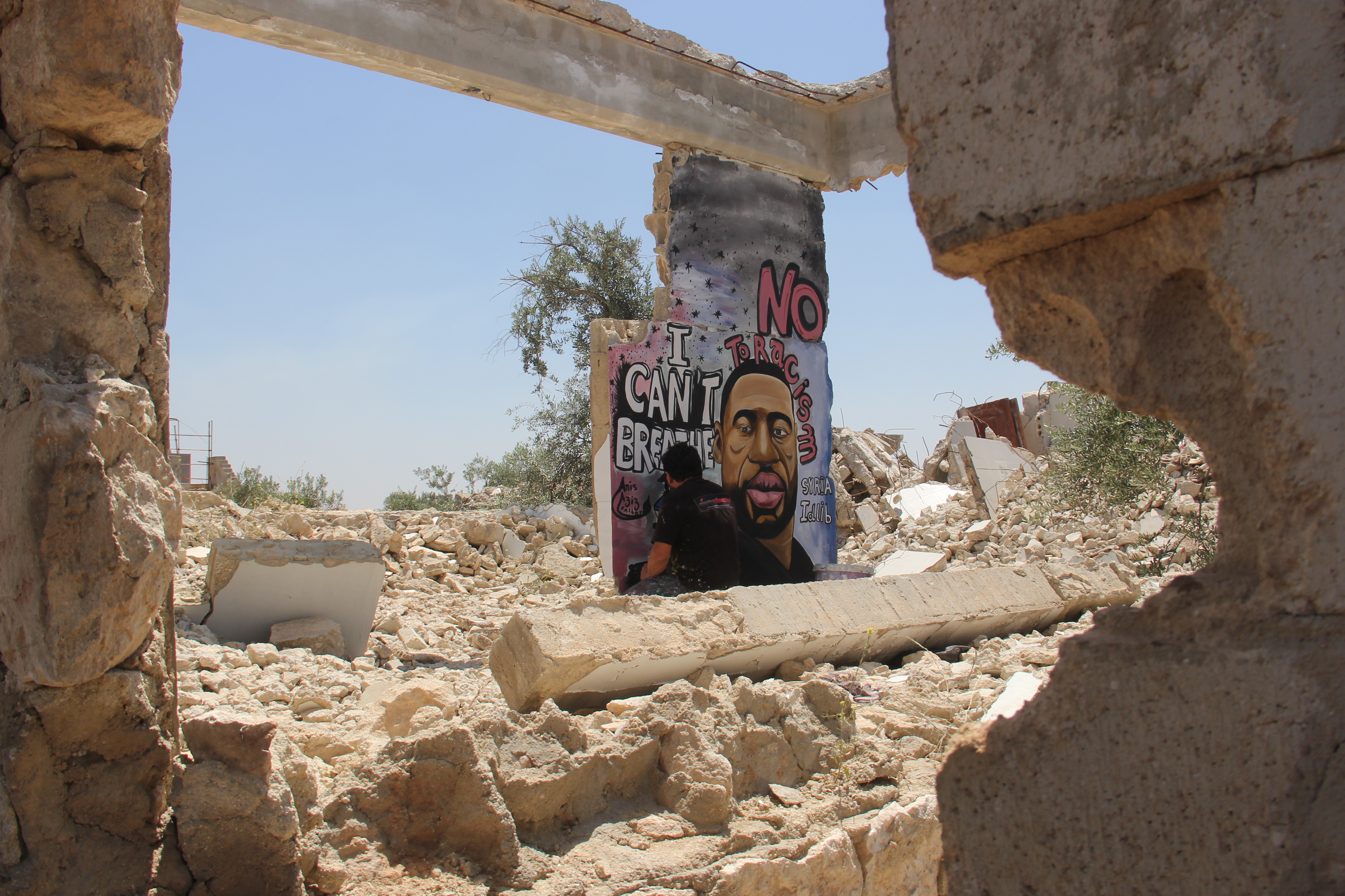 Syrian artist Aziz Alasmar paints a mural of George Floyd on the remains of a collapsed building in Binnish, a town in Syria's Idlib province. (Mohamad Jamalo)