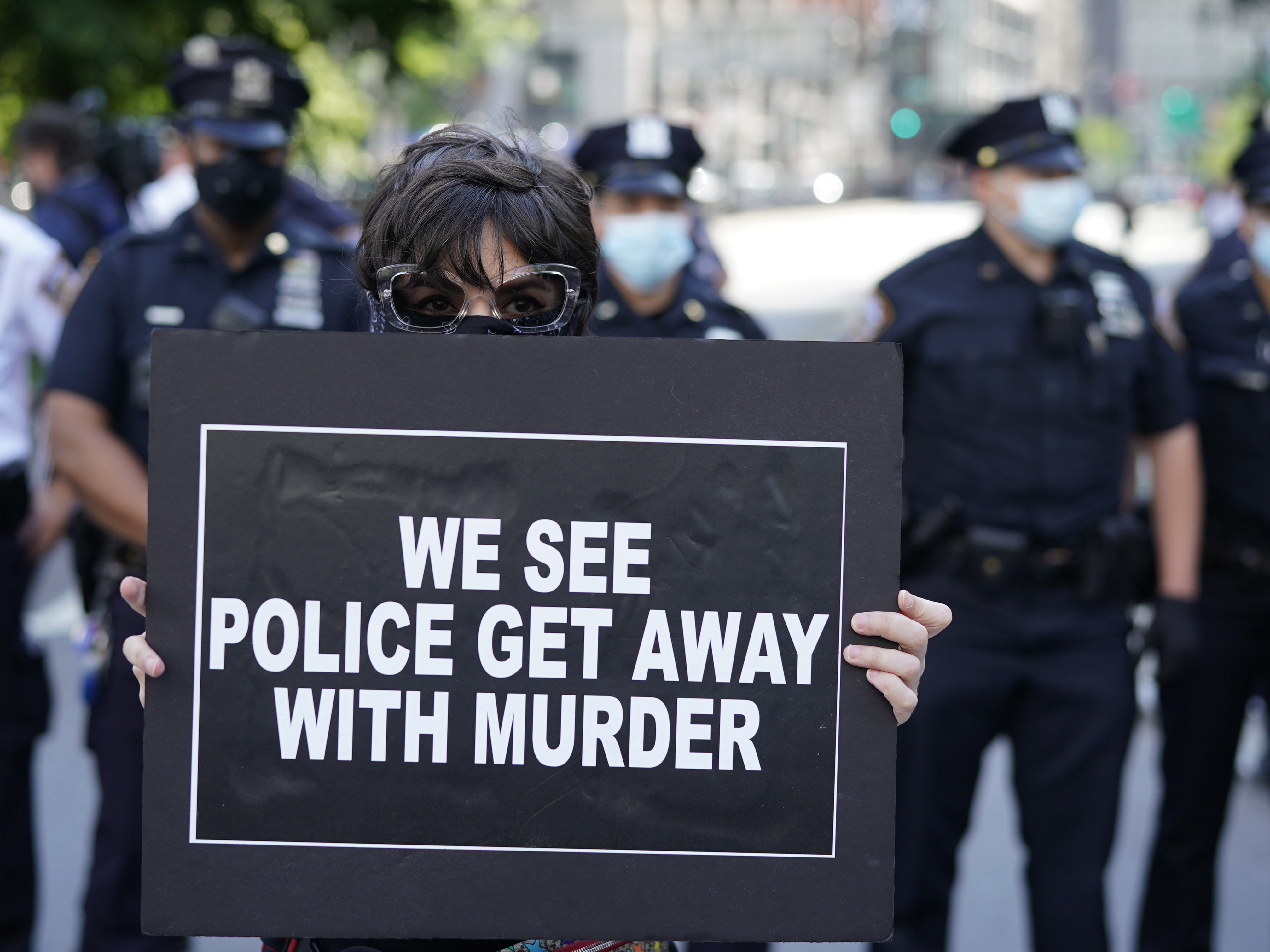 New York City Police officers stand behind a protester during a vigil at Foley Square in New York last month. (AFP via Getty Images)