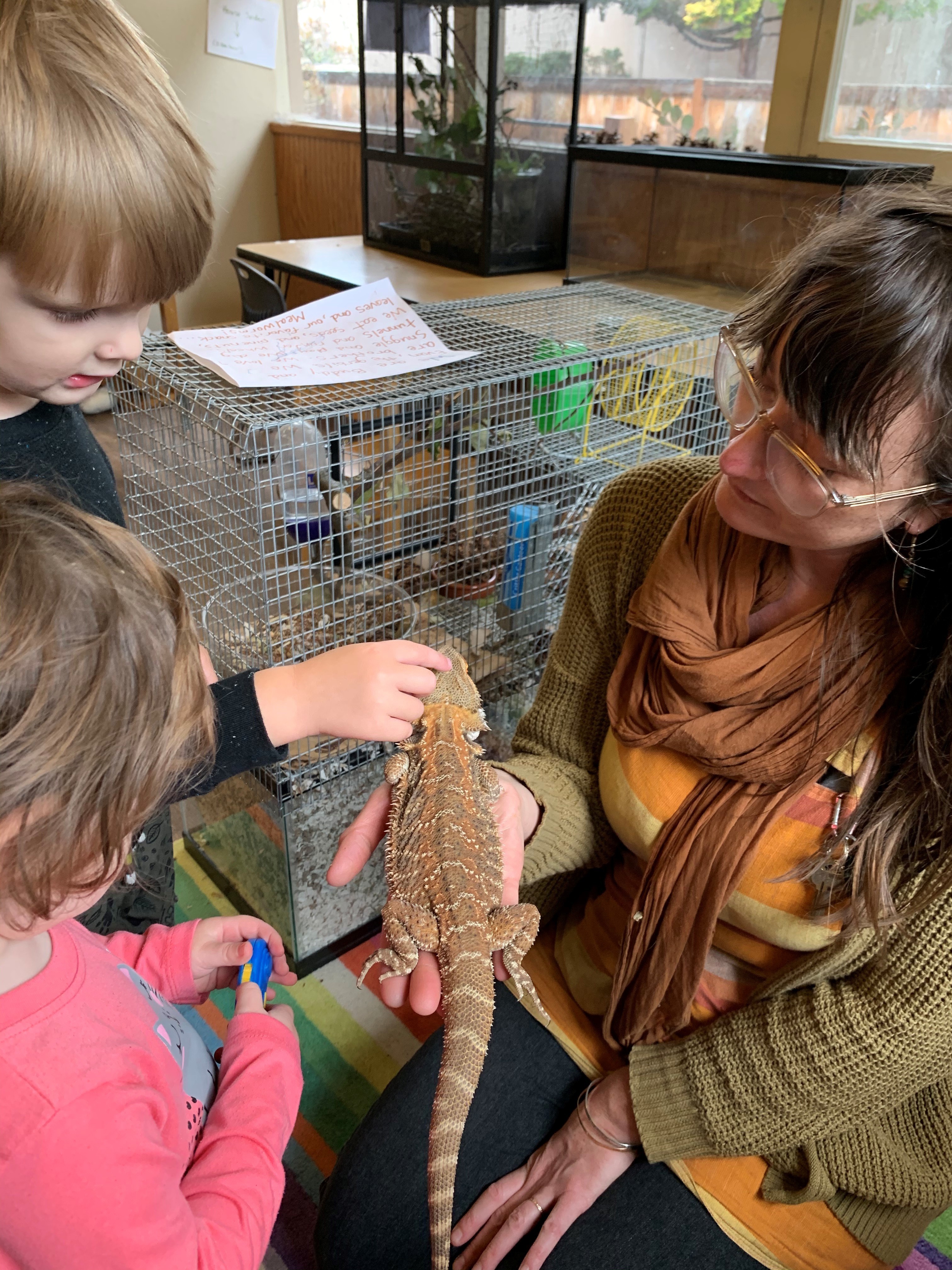 Lainy Morse shows students Wesley Schmidt and Celeste Abraldes a bearded dragon in a photo taken when school was open. (Lainy Morse)