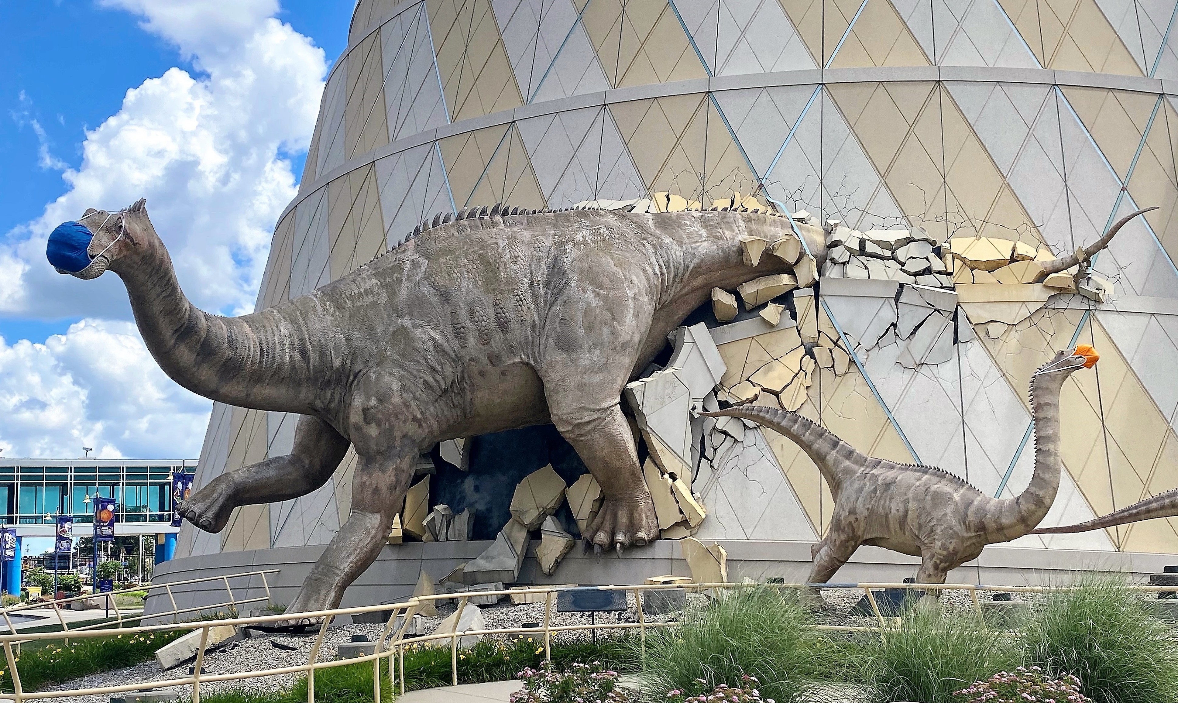 A life-sized dinosaur family wearing masks bursts from the walls of The Children's Museum of Indianapolis, the largest children's museum in the world. (The Children's Museum of Indianapolis)