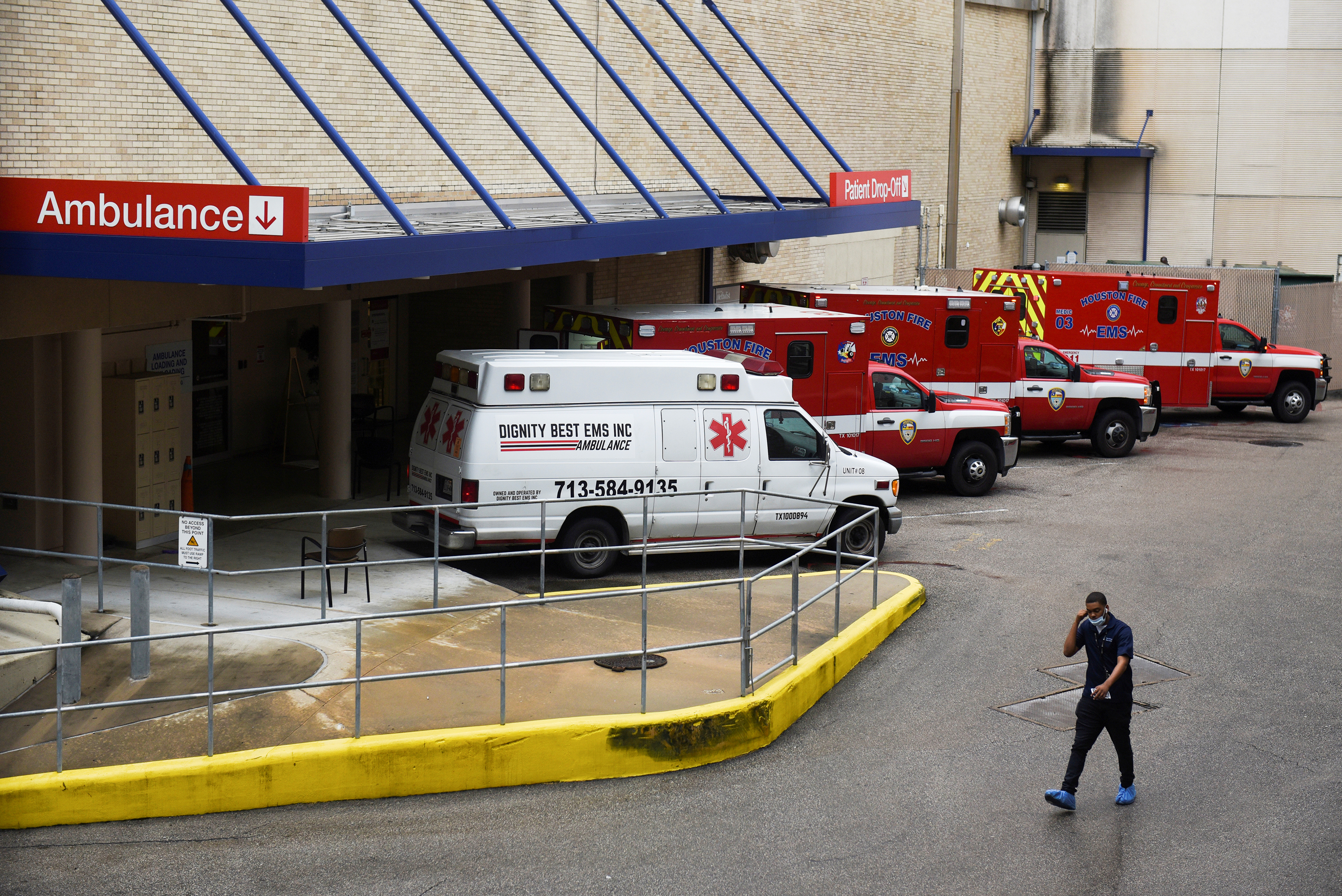 A medical worker walks past a row of ambulances parked outside Houston Methodist Hospital on June 22. The hospital is treating a current surge of COVID-19 cases. (Reuters)