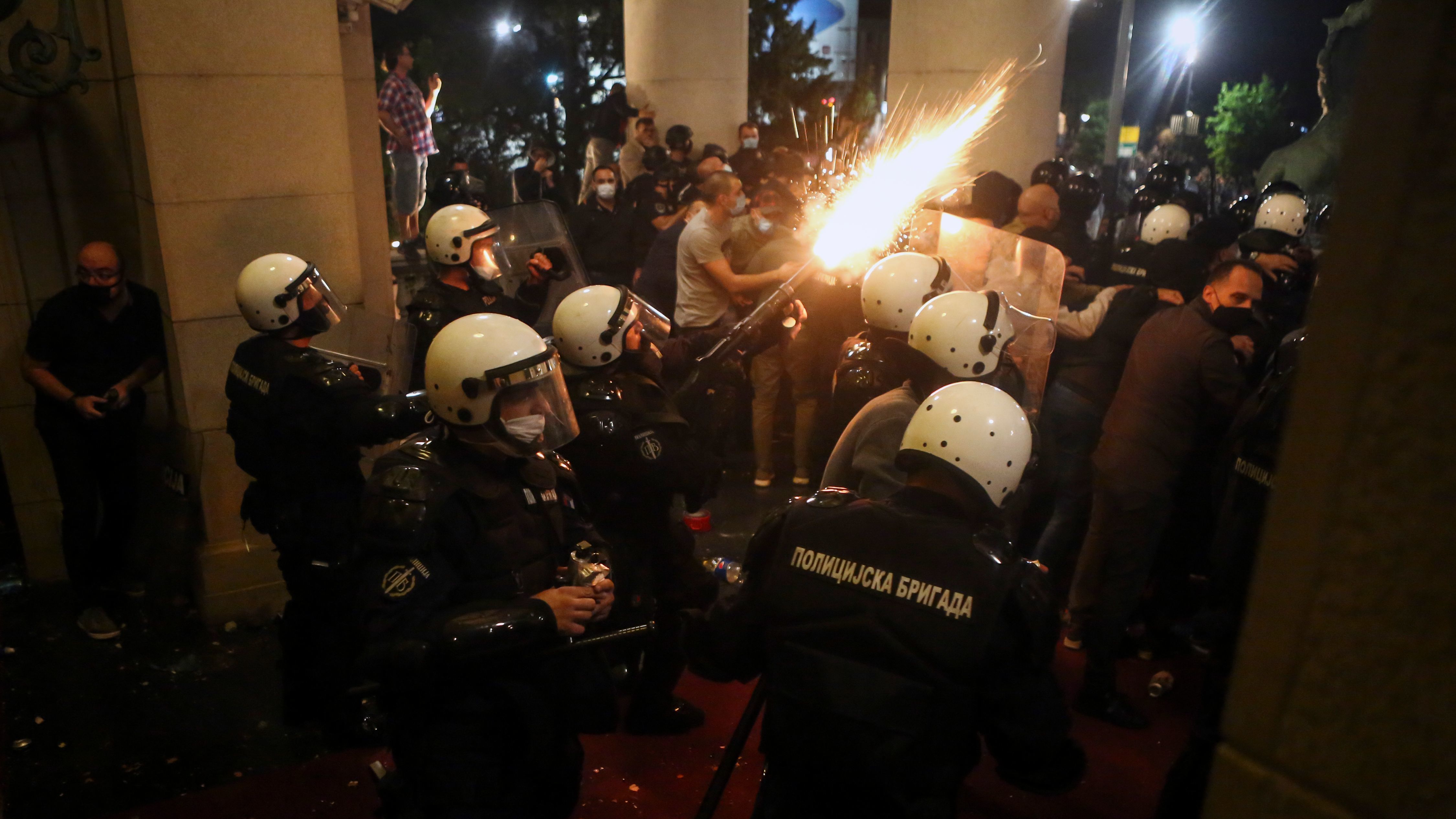 Protesters clash with police in front of the National Assembly building Tuesday night in Belgrade.