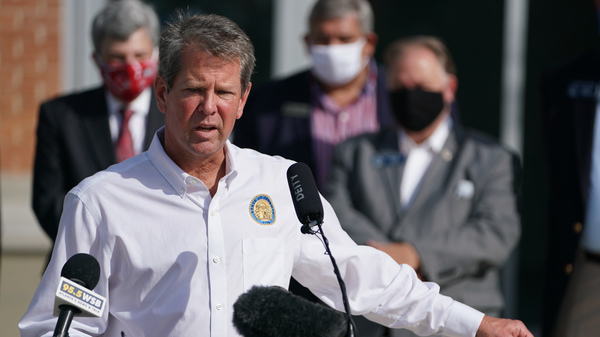 Georgia Gov. Brian Kemp holds a protective mask while speaking during a