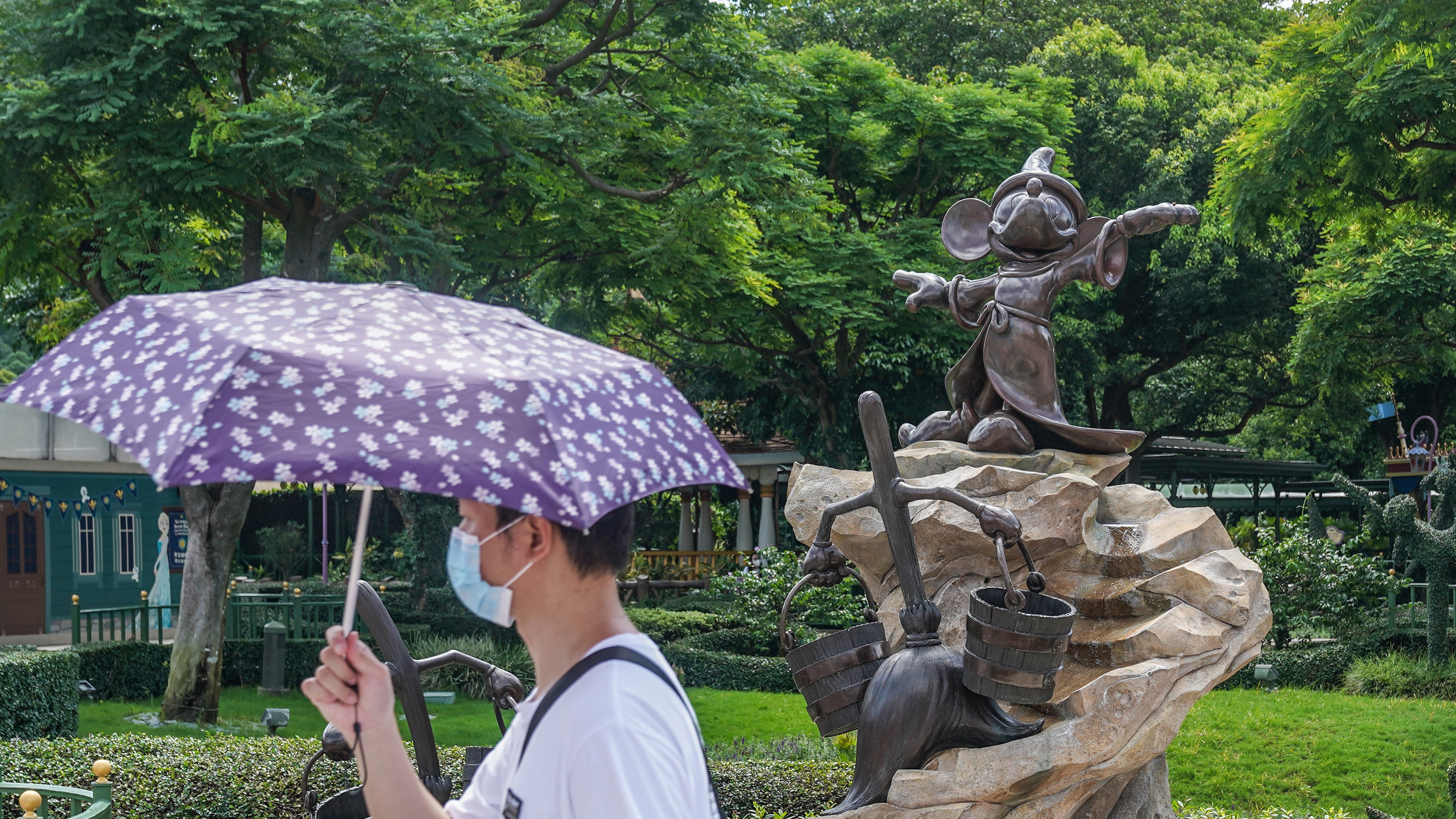 A visitor wearing a protective mask walking past a statue of Mickey Mouse at the Disneyland Resort in Hong Kong on the day it initially reopened, June 18. The amusement park will close again on Wednesday.