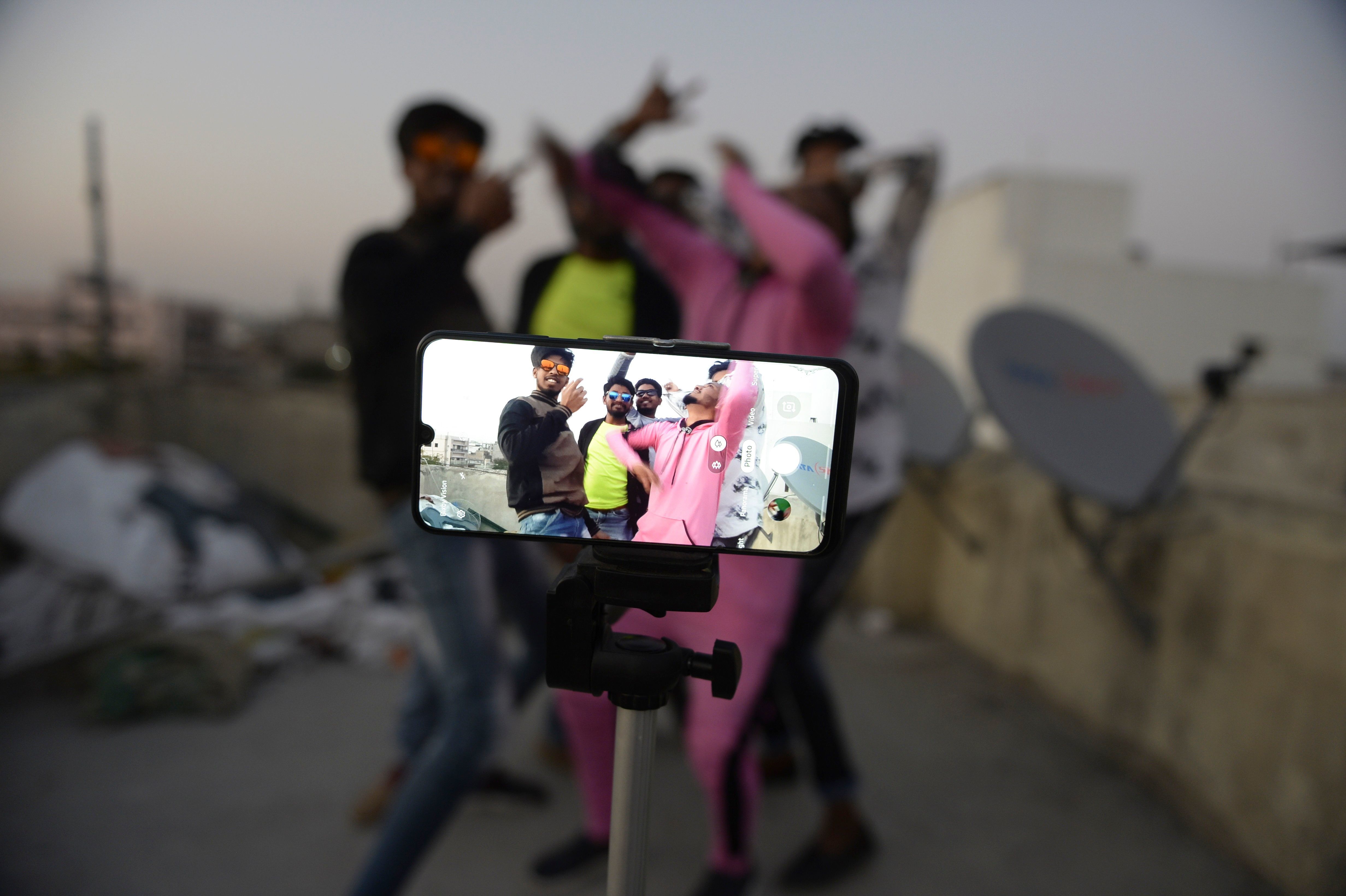 Youths perform in front of a cellphone camera while making a TikTok video on the roof of their residence in Hyderabad, India, in February. India's government has banned 59 Chinese-owned apps including TikTok. (AFP via Getty Images)
