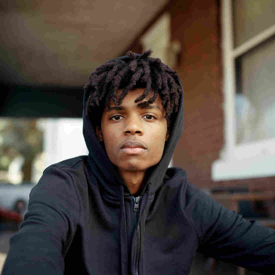 Khaya sitting on the porch wearing a black hoodie.