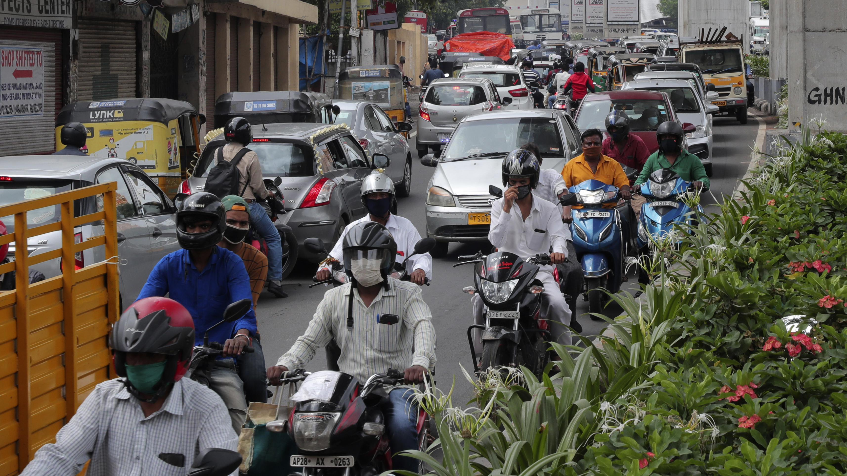 People wearing face masks ride past a busy street on Friday in Hyderabad, India. India crossed 1 million coronavirus cases on Friday, third only to the United States and Brazil.