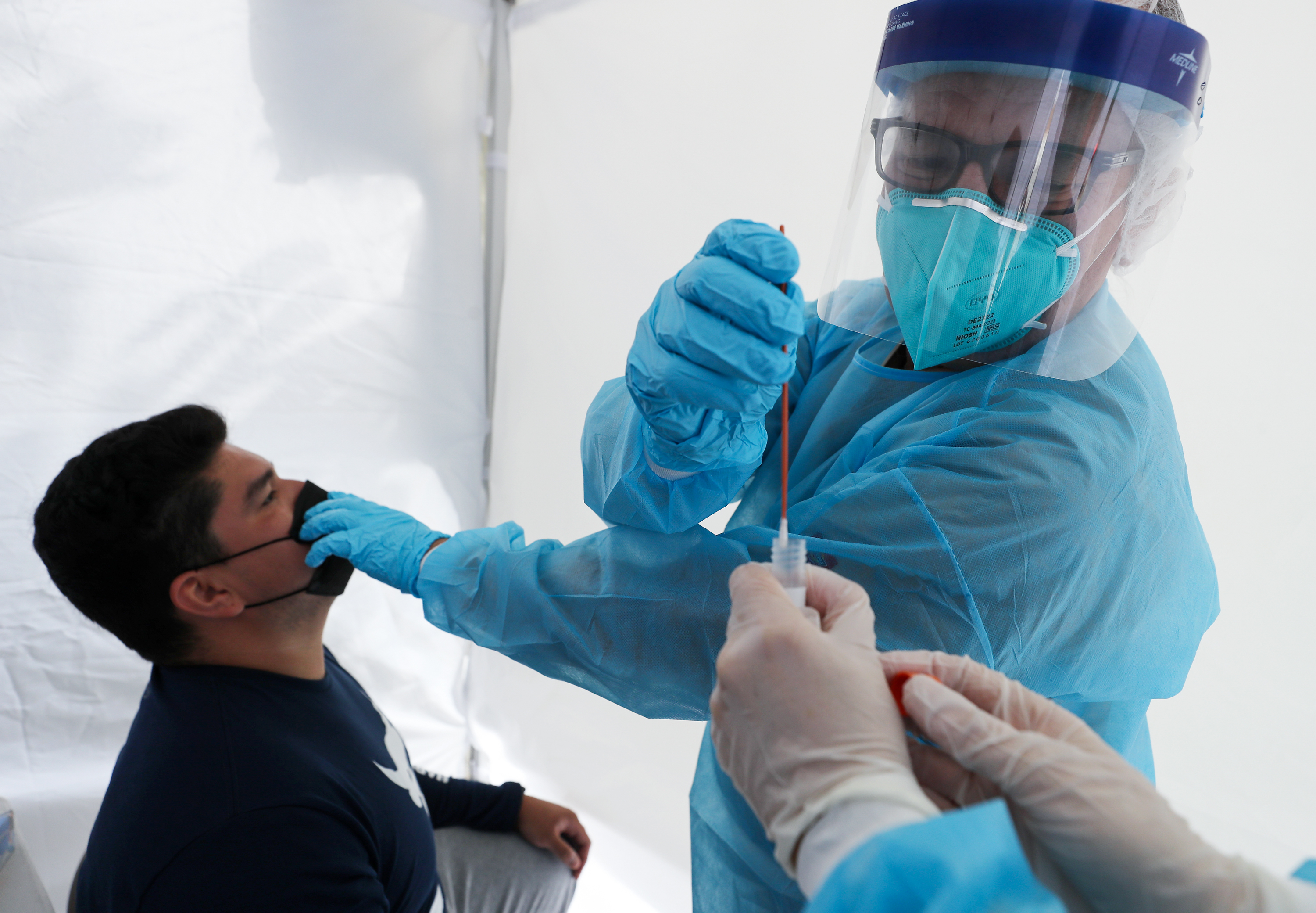 Dr. Glenn Lopez administered a standard test for the coronavirus to Daniel Contreras at a mobile clinic in South Los Angeles last week. Though highly accurate, such tests can take days or more to process. (Getty Images)