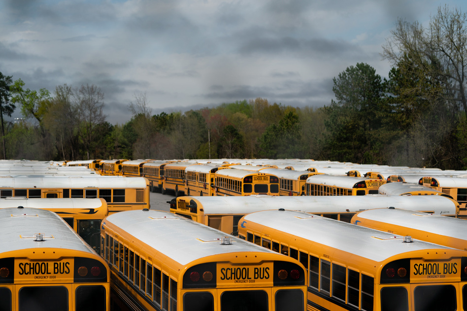 School buses sit parked at a lot in Marietta, Ga., in March. Georgia Gov. Brian Kemp has pushed for students to return to school in the fall, but the state's largest system, in Gwinnett County, has decided on all-virtual learning. (Elijah Nouvelage/Bloomberg via Getty Images)