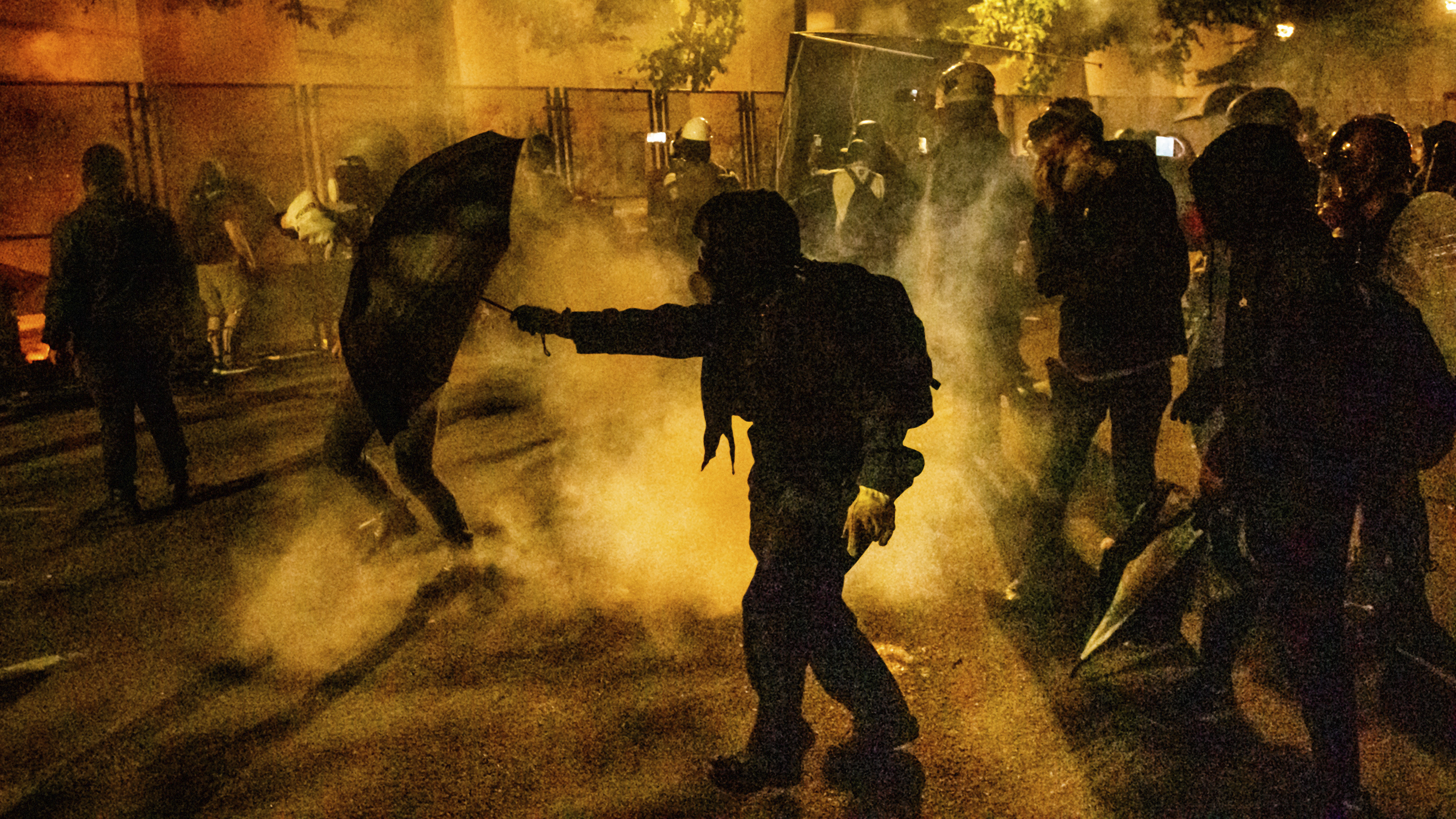 Protesters walk through chemical irritants deployed by federal agents in Portland, Ore. The Justice Department inspector general says he is investigating federal officers