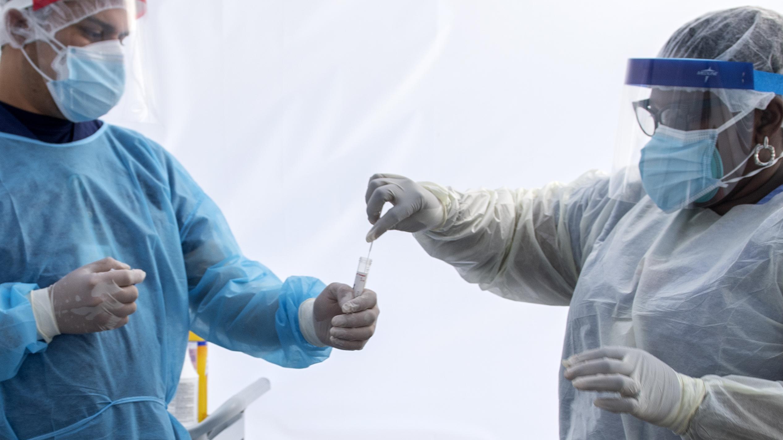 A health worker puts a nasal swab sample into a tube in a tent at a COVID-19 testing site at St. John