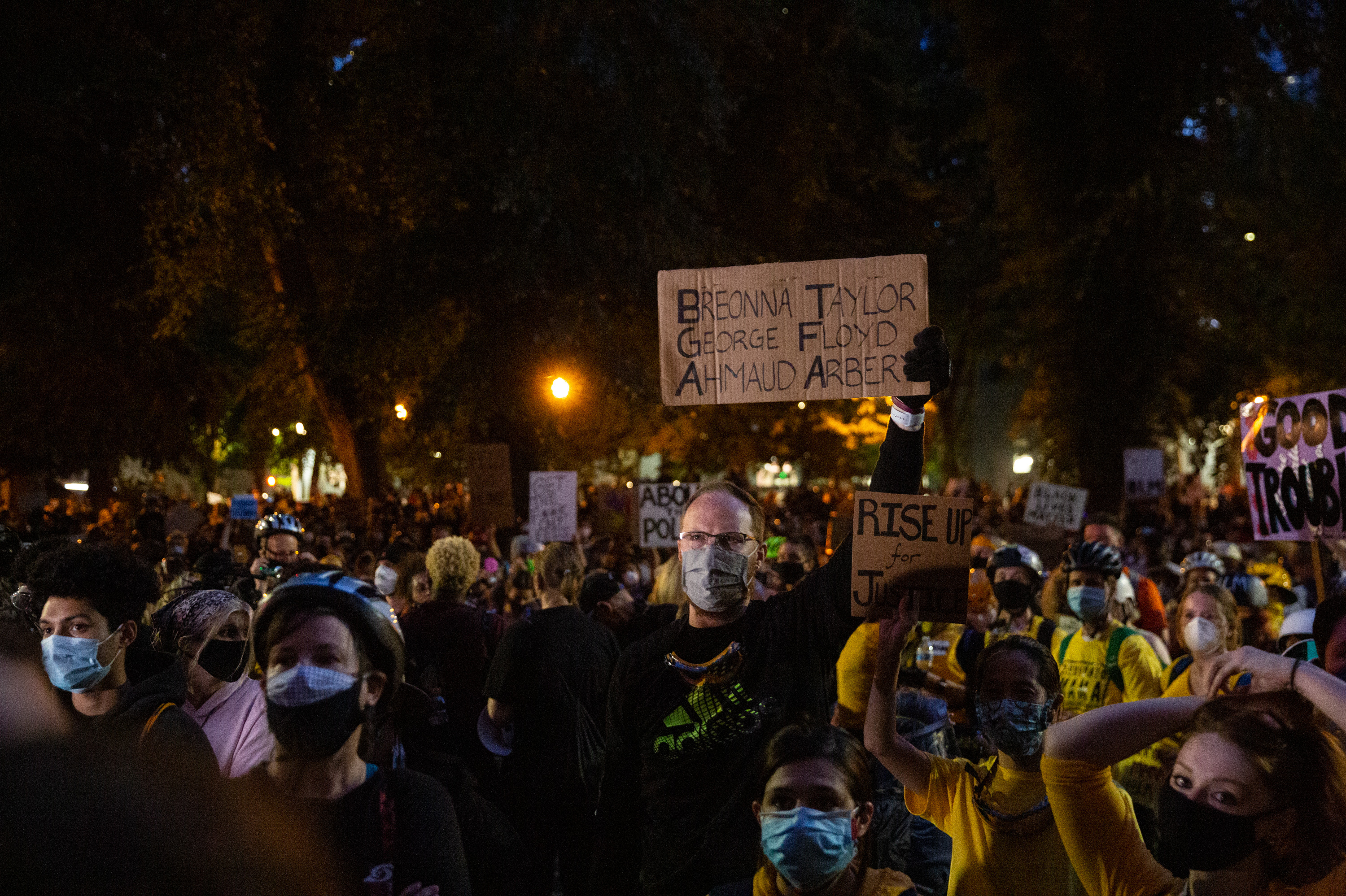 A man holds a sign with the names of Breonna Taylor, George Floyd and Ahmaud Arbery in Portland on Saturday. (Bradley W. Parks/OPB)