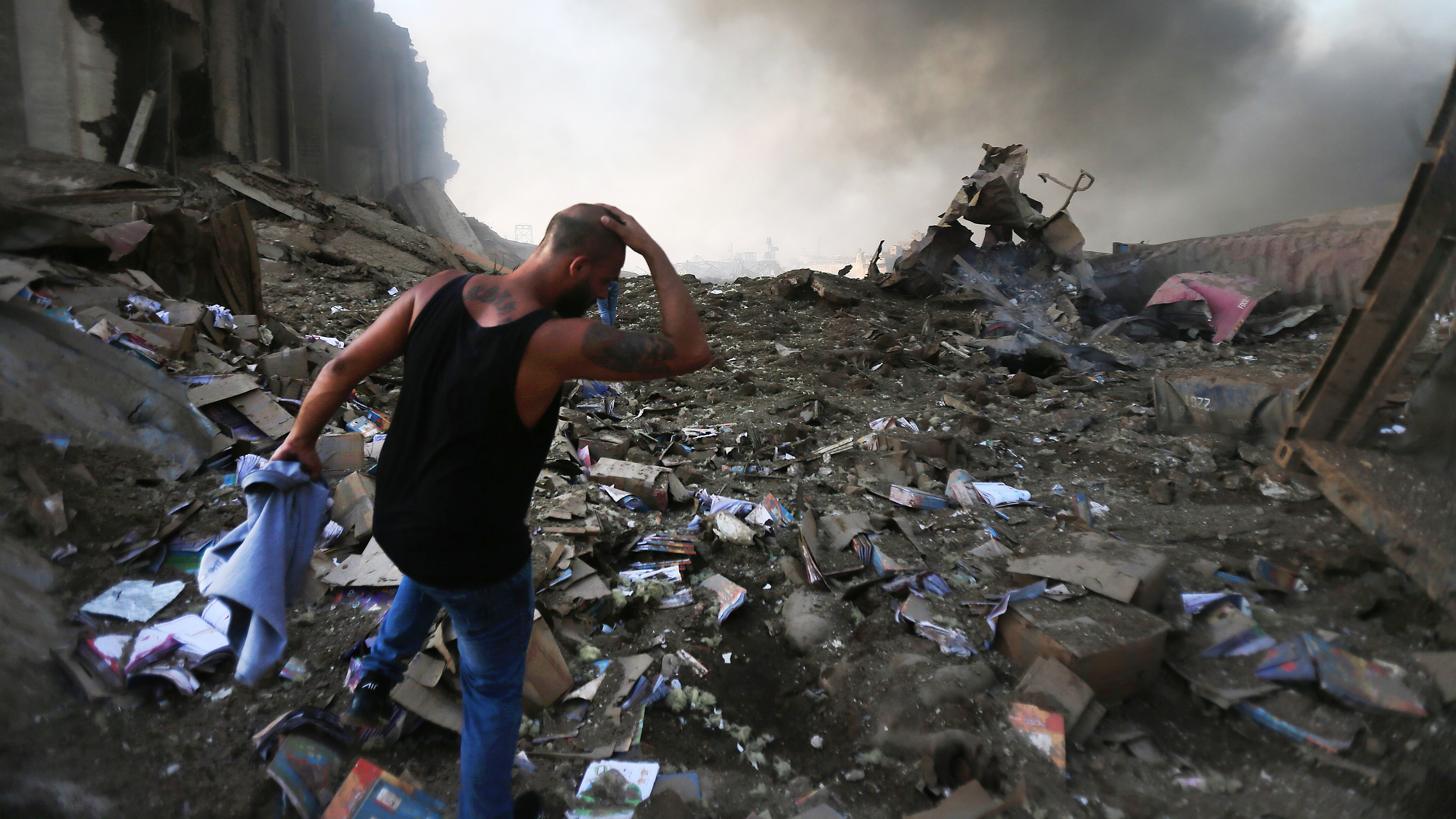 A man walks through debris near the scene of an enormous explosion in Lebanon on Tuesday. At least 70 people are killed and at least 2,700 people were hurt. The blast shattered windows and damaged buildings across a wide swath of the city.