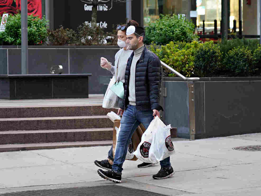 NEW YORK, NEW YORK - MARCH 26: People are seen wearing protective masks while smoking as the coronavirus continues to spread across the United States on March 26, 2020 in New York City. (Photo by Cindy Ord/Getty Images)