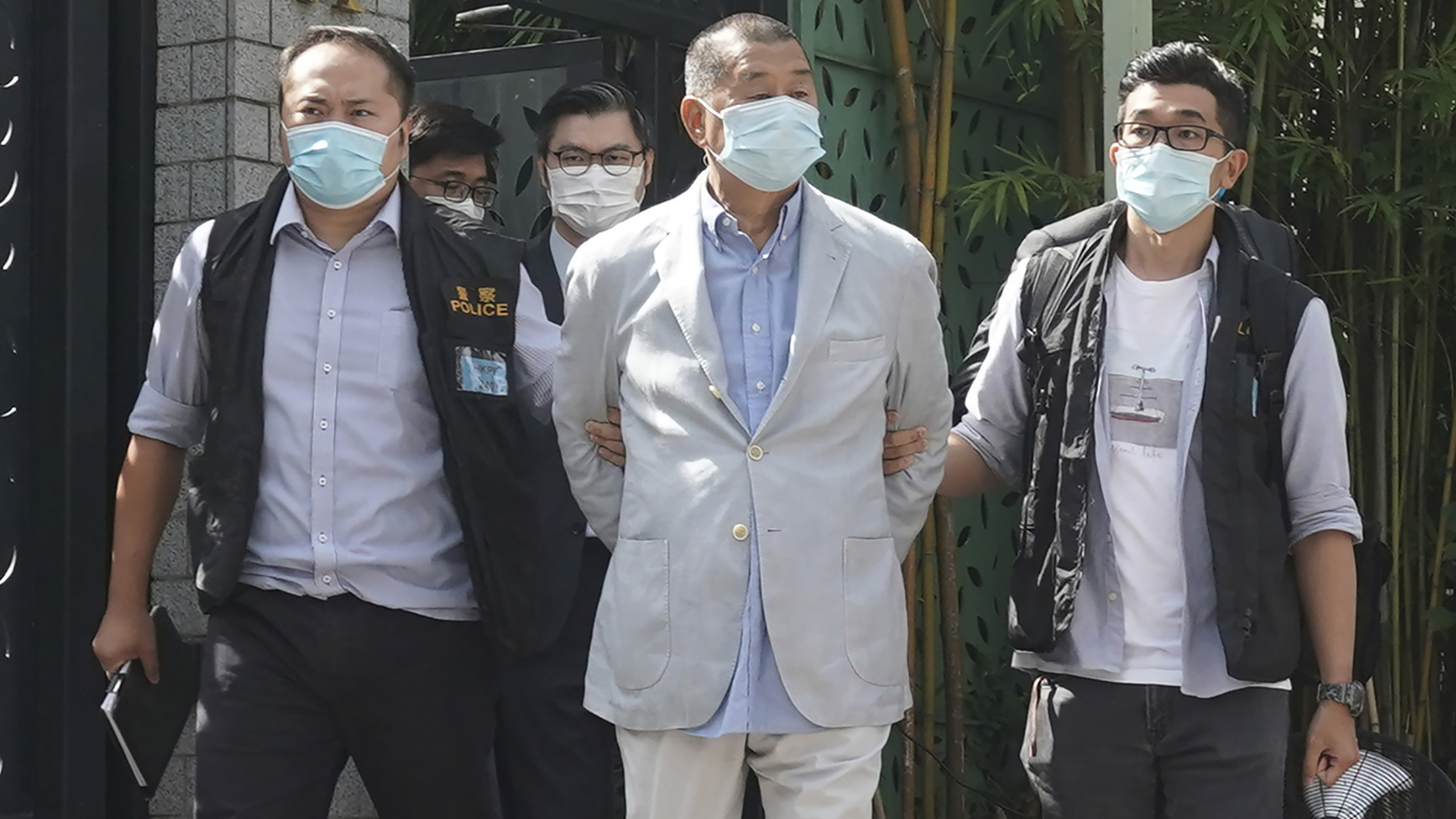 Hong Kong media tycoon Jimmy Lai, center, is arrested by police officers at his home in Hong Kong on Monday. Hong Kong police arrested Lai and raided the publisher