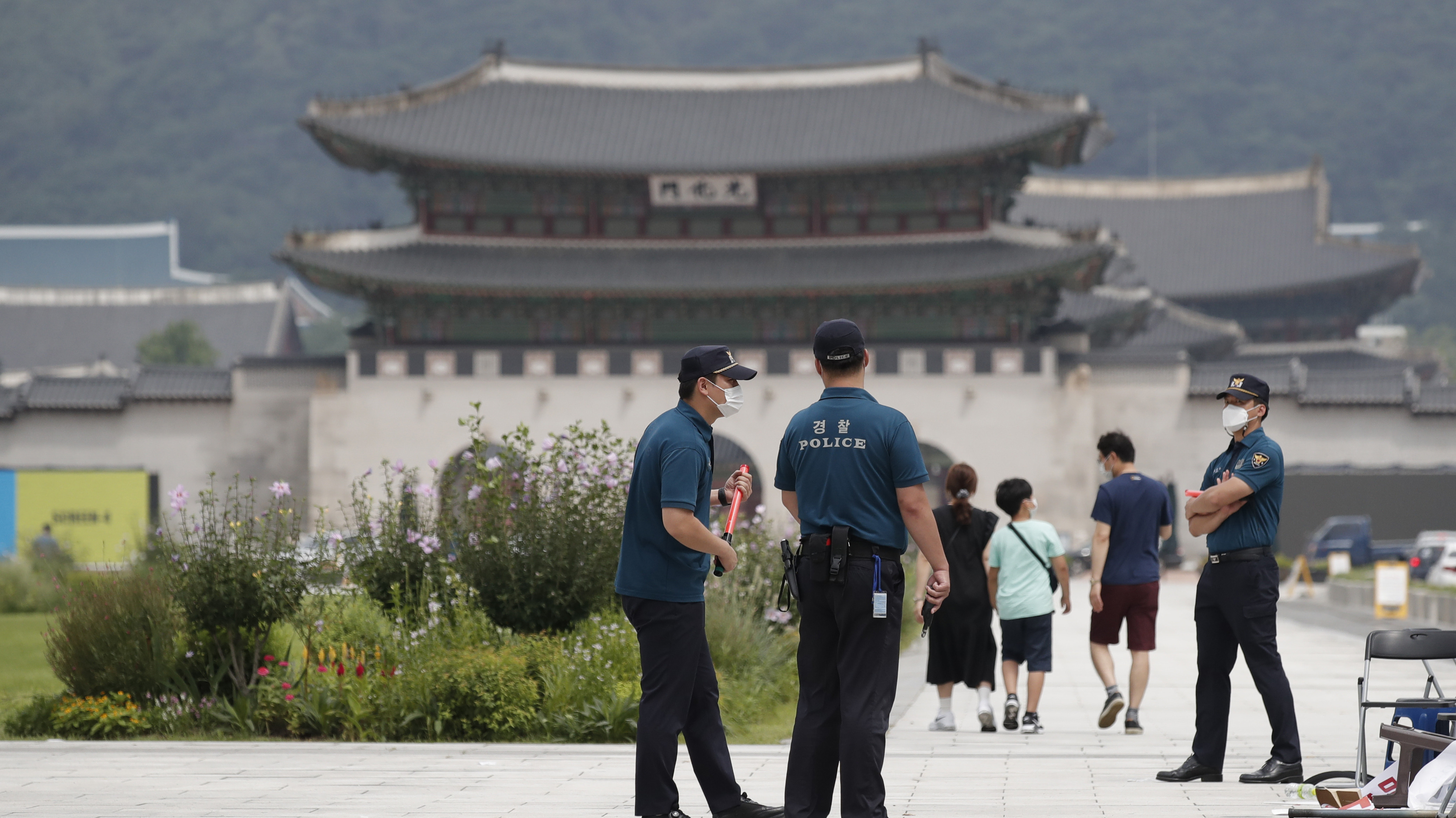 Police officers and visitors wearing face masks to help protect against the spread of the coronavirus, walk in downtown Seoul, South Korea, Sunday.