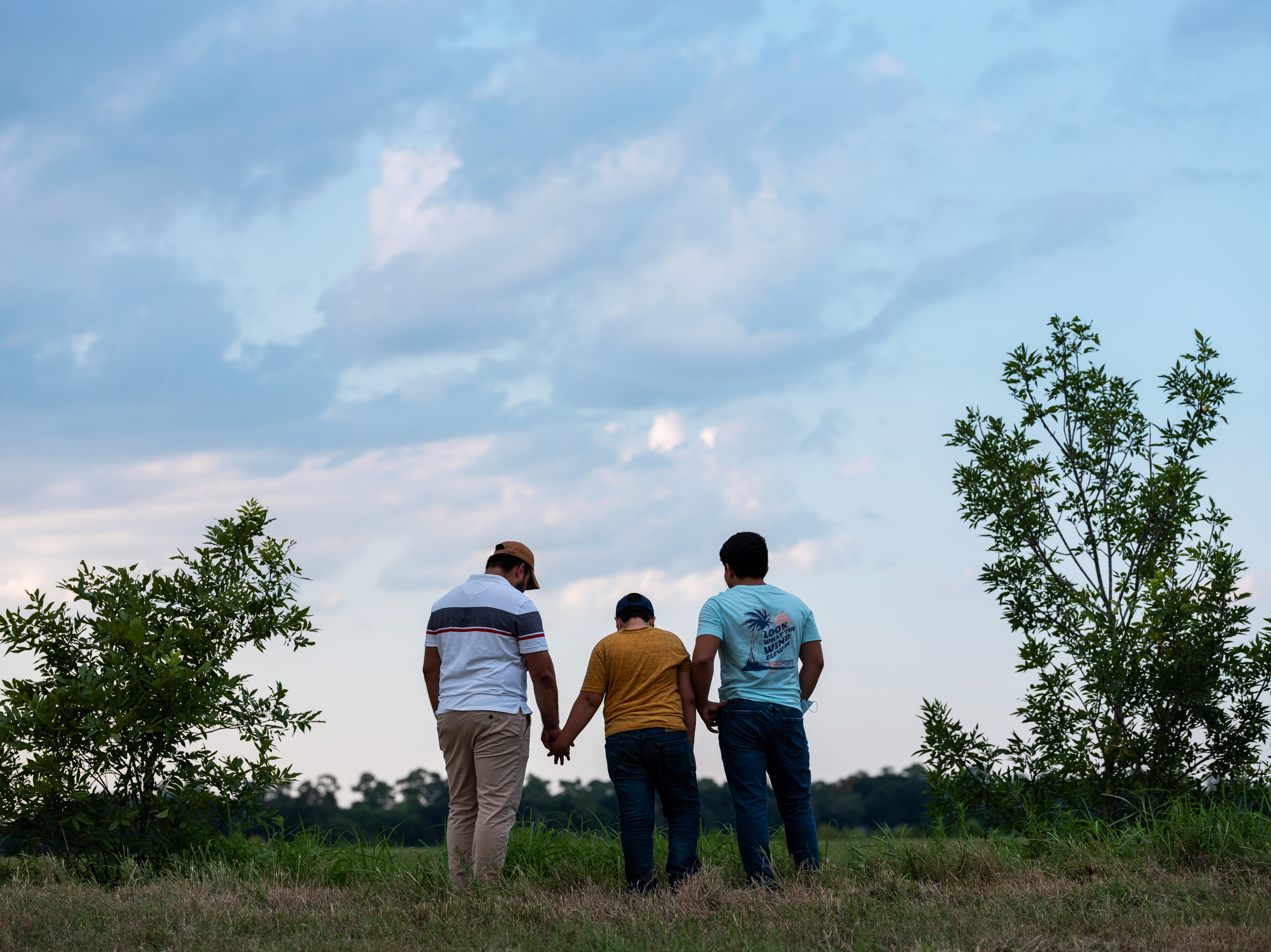 Honduran migrants, Ricardo Sr., (left), his son Ricardo Jr., 13, and his cousin Jorge, 16, walk near their home in Texas. When the two teenage boys crossed the border illegally into Texas last month, they turned themselves in to the Border Patrol. They were later escorted to a hotel by armed men in civilian clothes. (Scott Dalton for NPR)