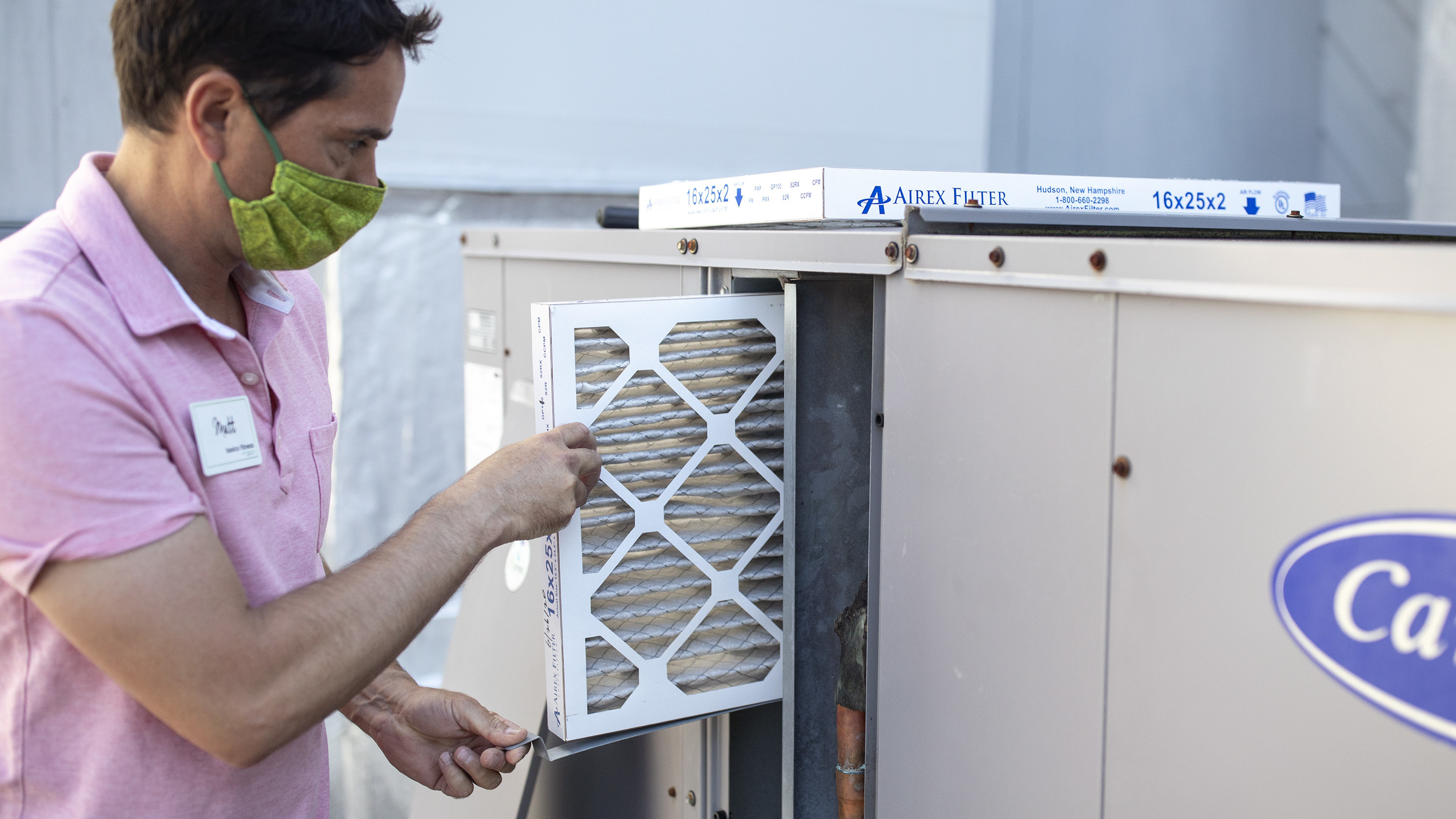 Mark Marston slides a MERV 13 air filter into the HVAC system outside Basics Fitness Center in Portland, Maine, on July 21. The gym bought these filters and made other changes to its ventilation, including bringing in more outside air, to help reduce the spread of the coronavirus. (Portland Press Herald via Getty Images)