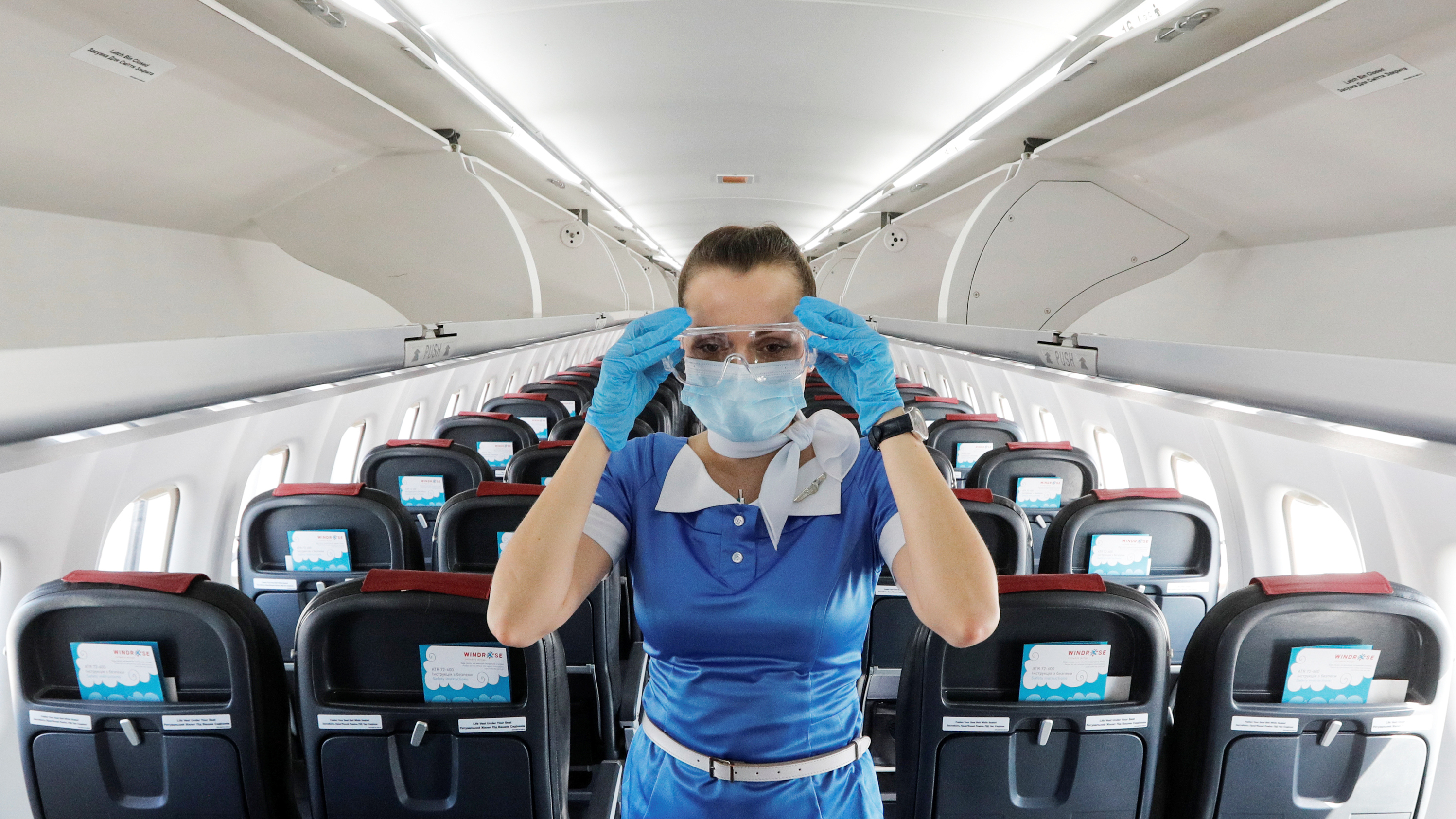 A flight attendant adjusts protective glasses. There has been little documentation about COVID-19 transmission on planes.