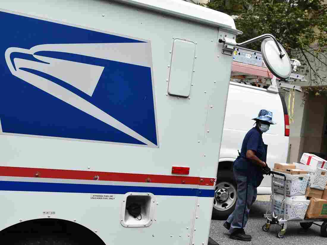 A mail carrier delivers mail to an apartment building in Bethesda, Maryland on August 21, 2020. (Photo by MANDEL NGAN / AFP) (Photo by MANDEL NGAN/AFP via Getty Images)