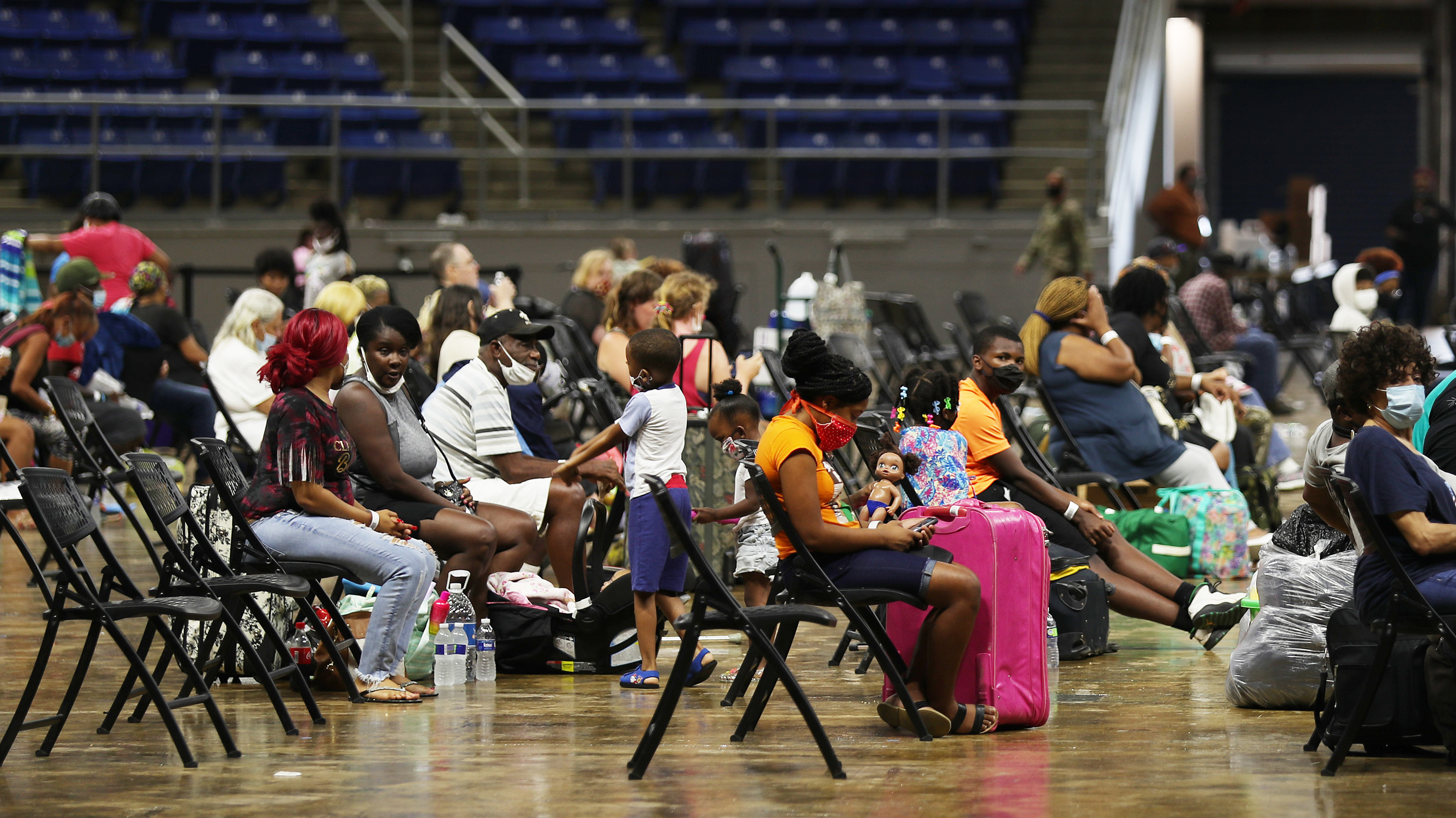 People wait to board buses as they are evacuated by local and state government officials before the arrival of Hurricane Laura on Tuesday in Lake Charles, Louisiana.