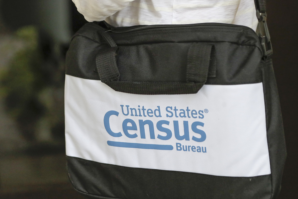 A U.S. Census Bureau worker carries a briefcase while knocking on the door of a home in August in Winter Park, Fla. (John Raoux/AP)