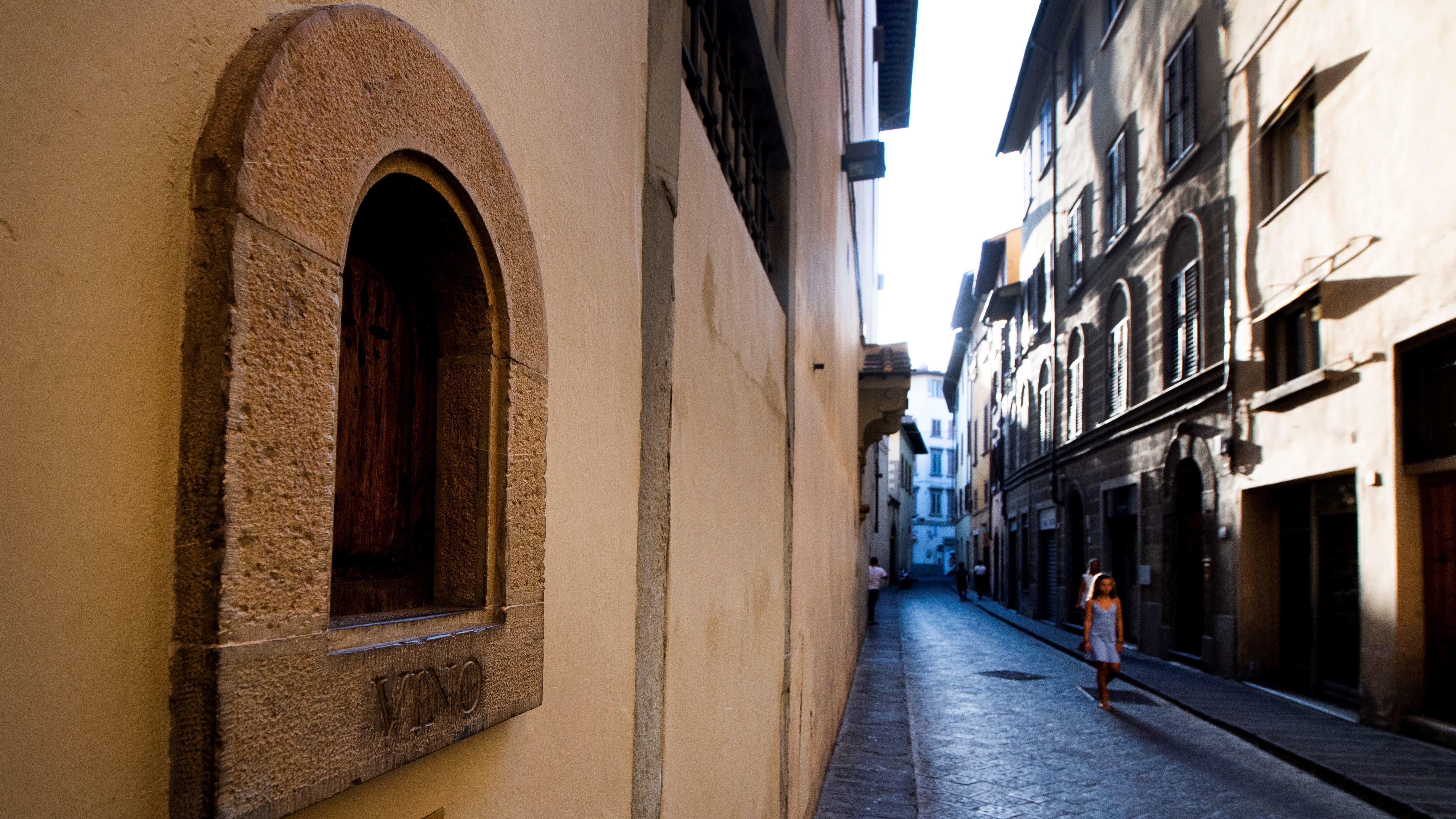 A girl walks past a buchetta del vino, a small window to serve wine, typical in Florence.
