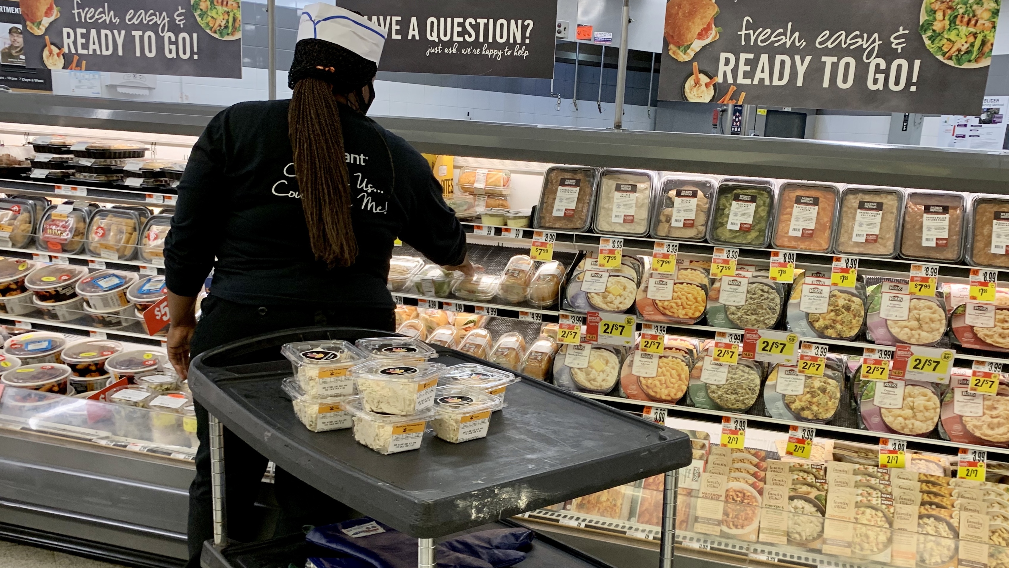 Grocery prices have fallen in recent months but are still 4.6% higher than at this time last year. Here, a woman stock shelves in a deli in June at a Washington, D.C., supermarket.