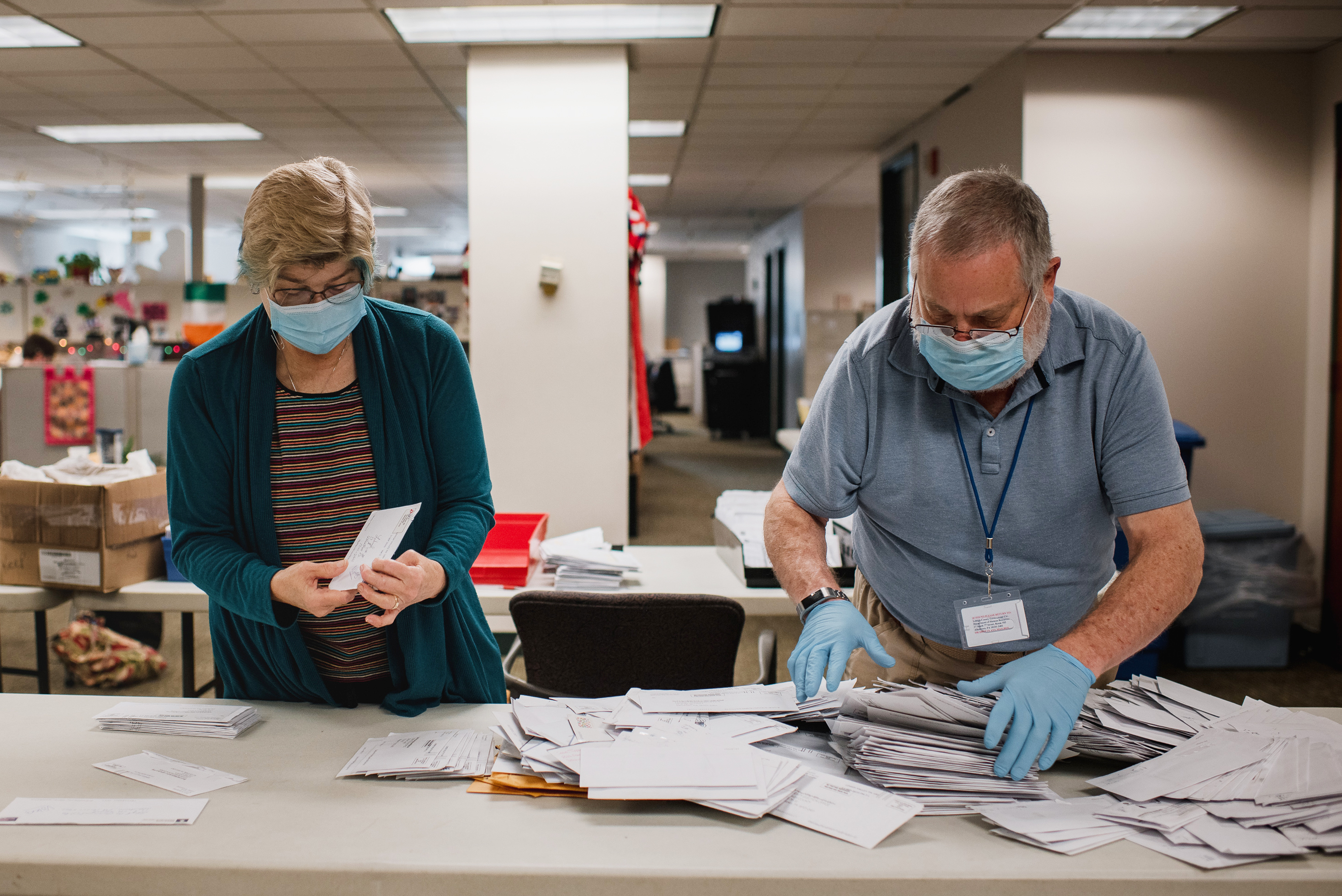 Andrea Lerner (left), and her husband, Ira Lerner, sift through the mail-in applications at the Voter Registration office in the Lehigh County Government Center in Allentown, Pa. (Hannah Yoon for NPR)